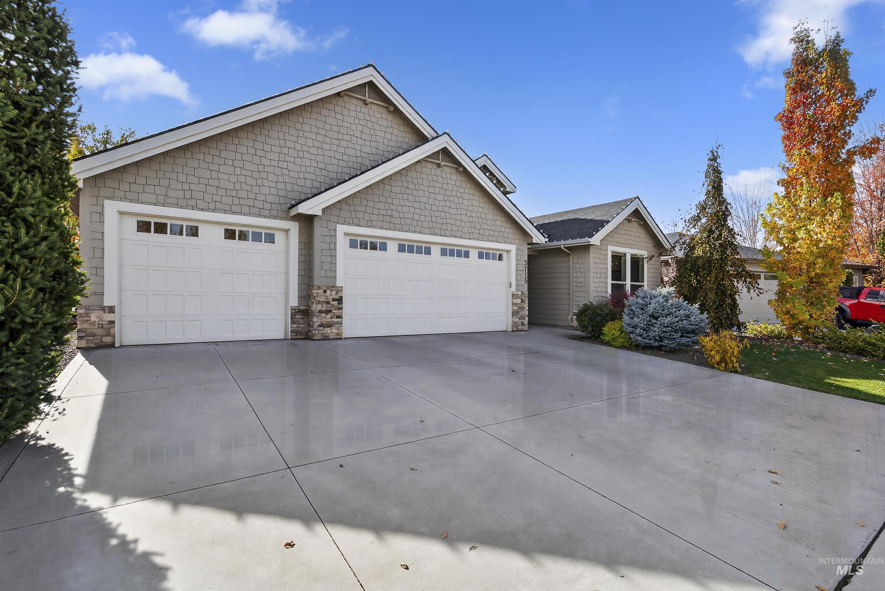 View of front of home with stone siding, driveway, and an attached garage