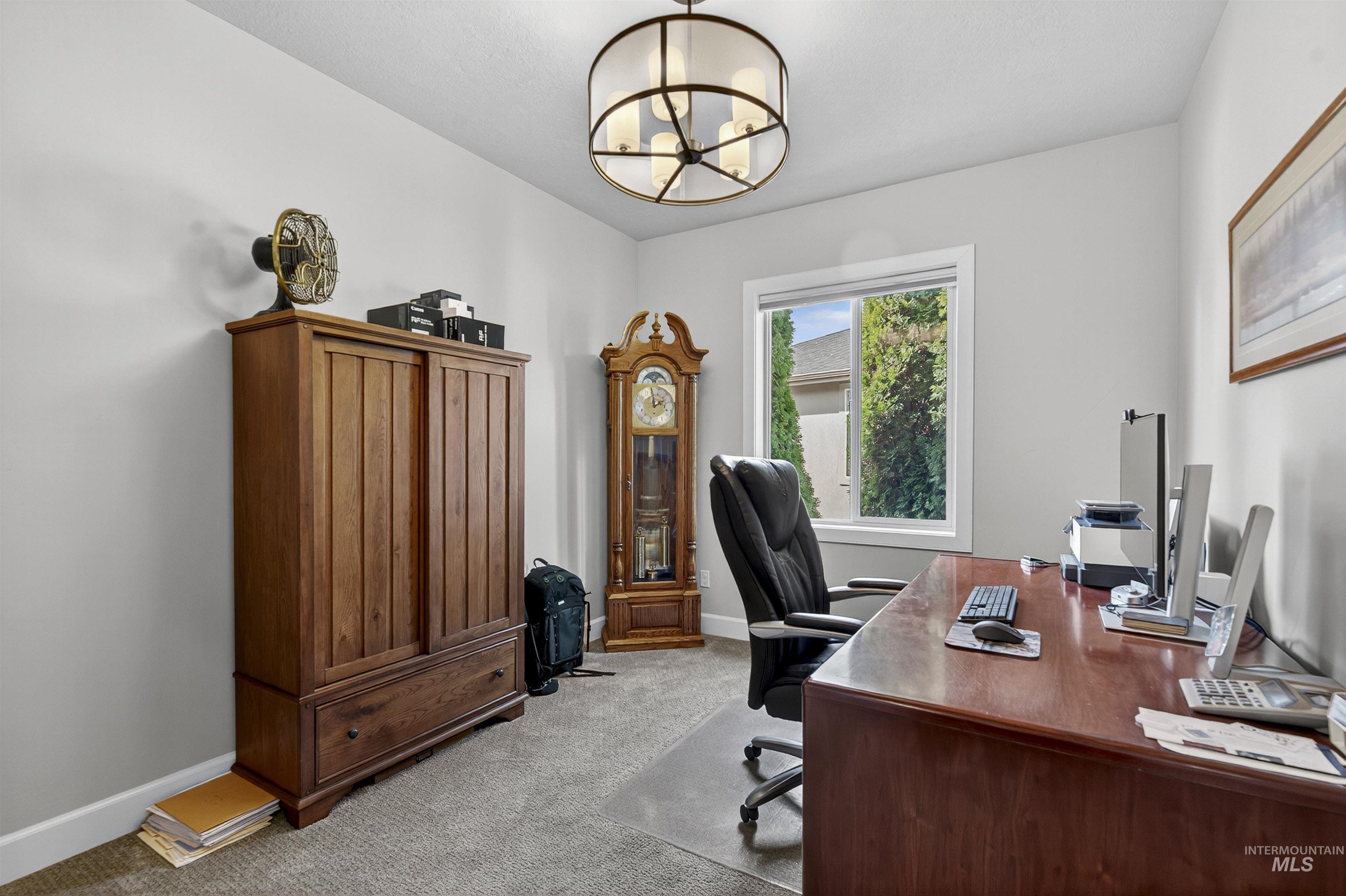 Office area featuring light carpet and a chandelier