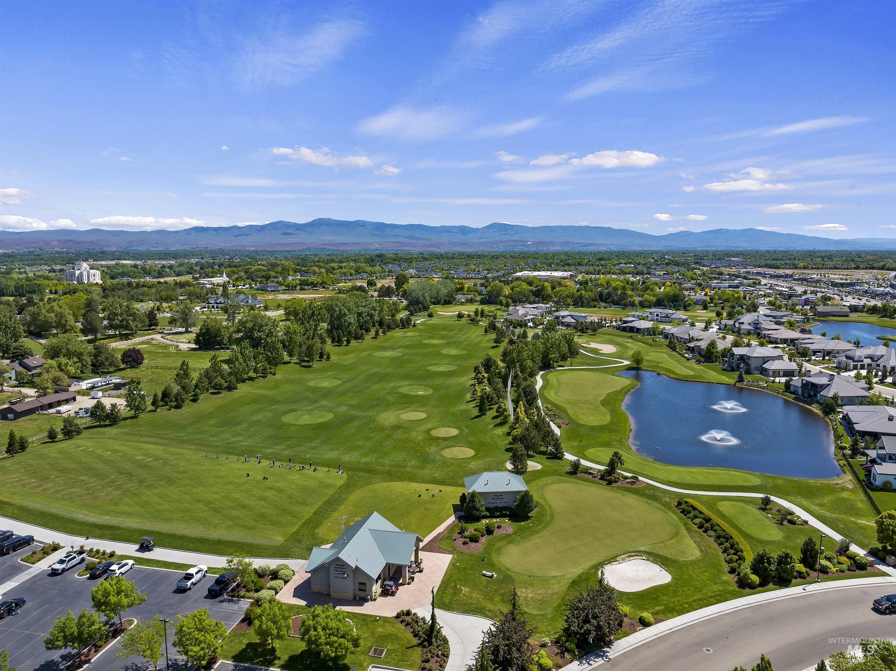 Aerial view of property and surrounding area featuring a water and mountain view, a golf club, and nearby suburban area