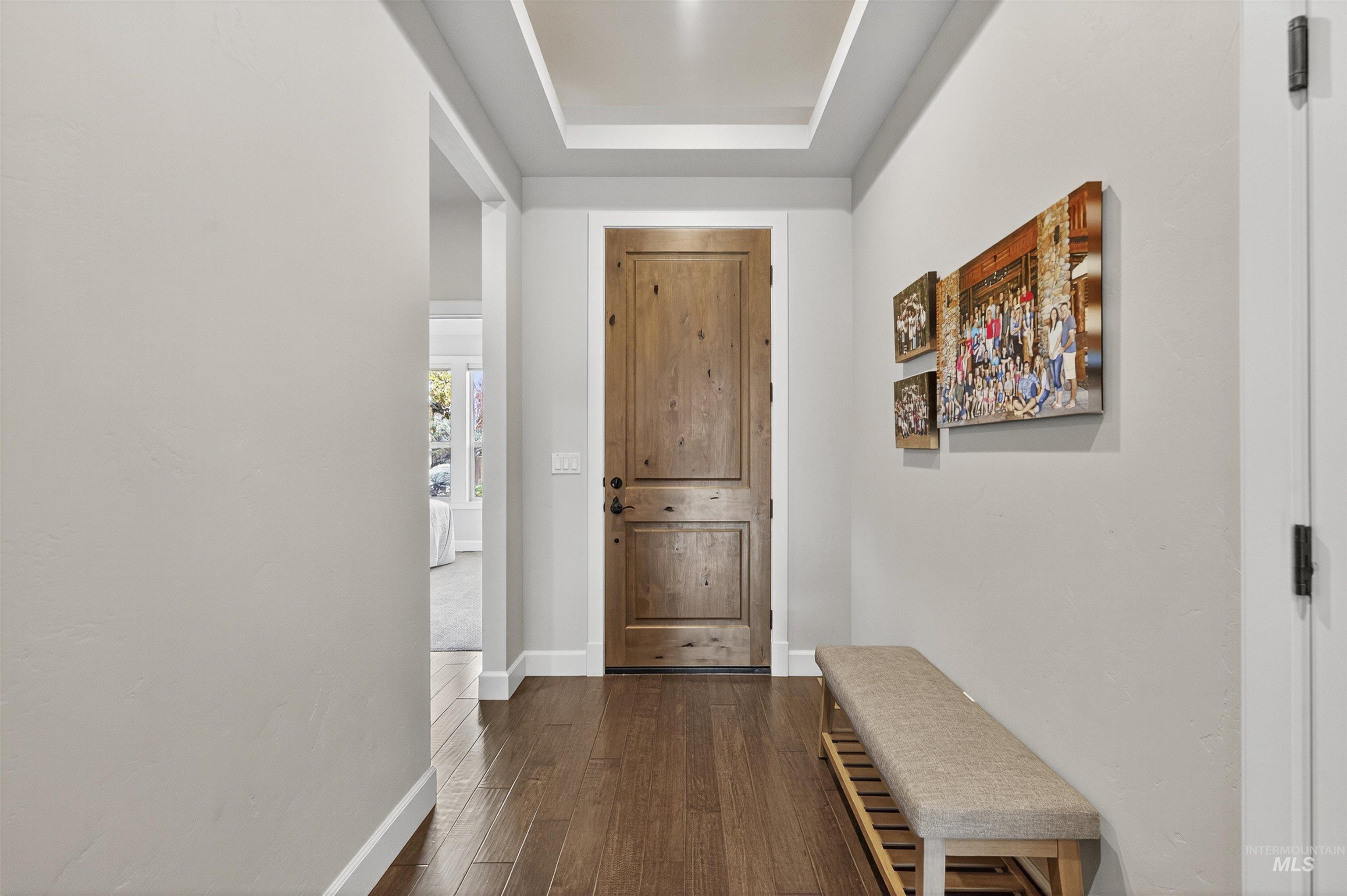 Hall featuring dark wood-type flooring and a tray ceiling