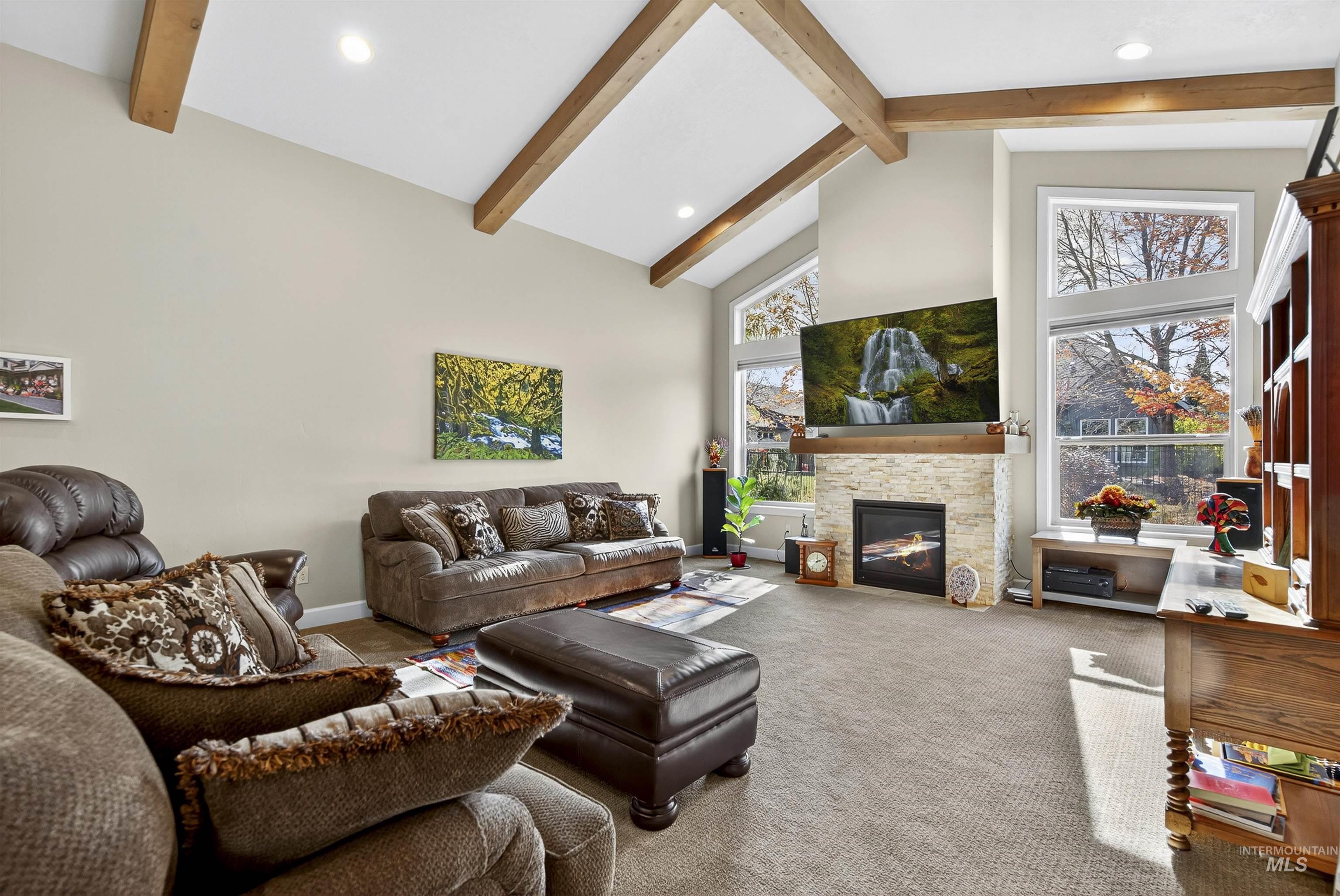 Carpeted living room with high vaulted ceiling, beam ceiling, recessed lighting, and a fireplace