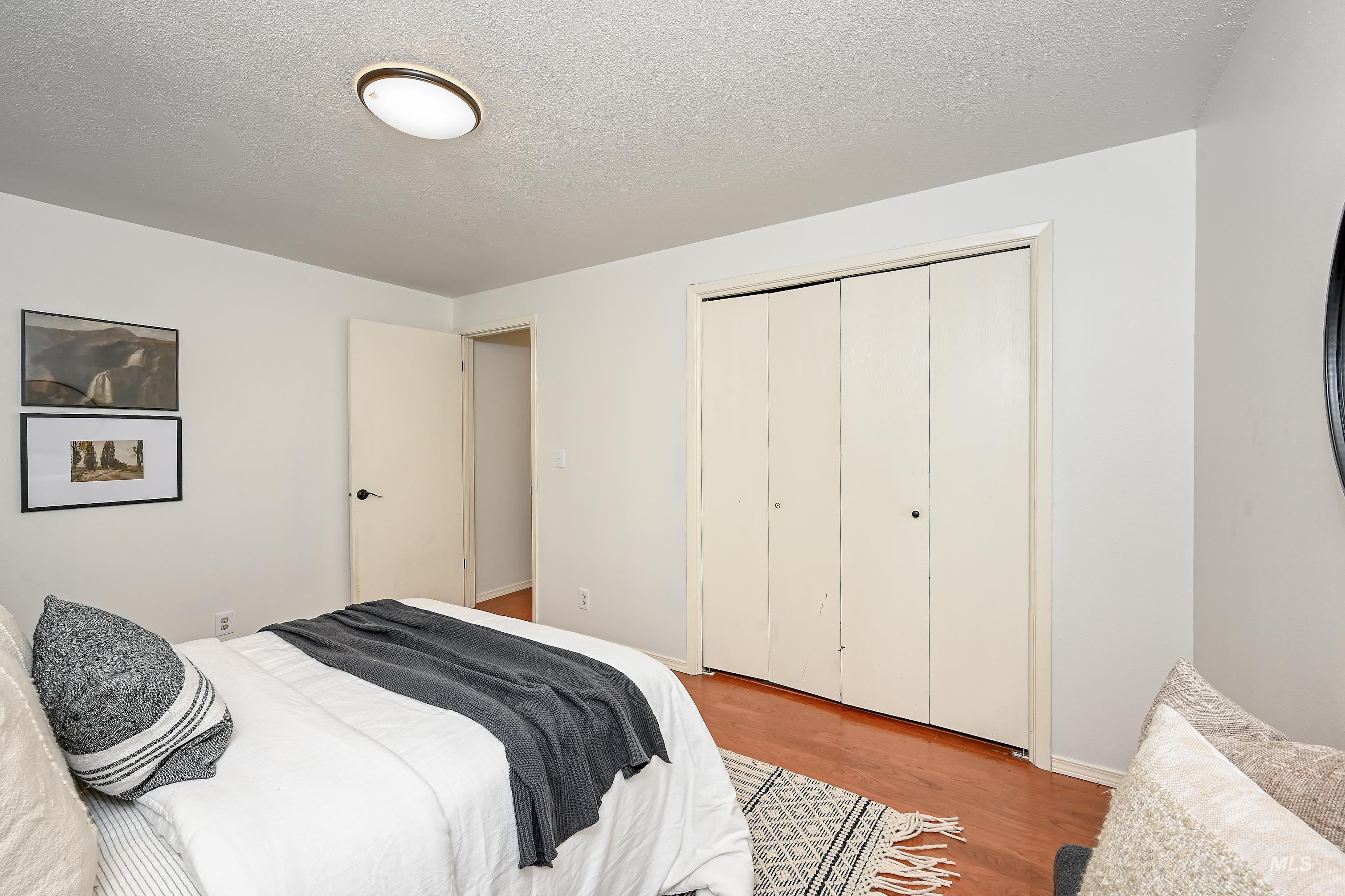Bedroom featuring wood finished floors, a textured ceiling, and a closet
