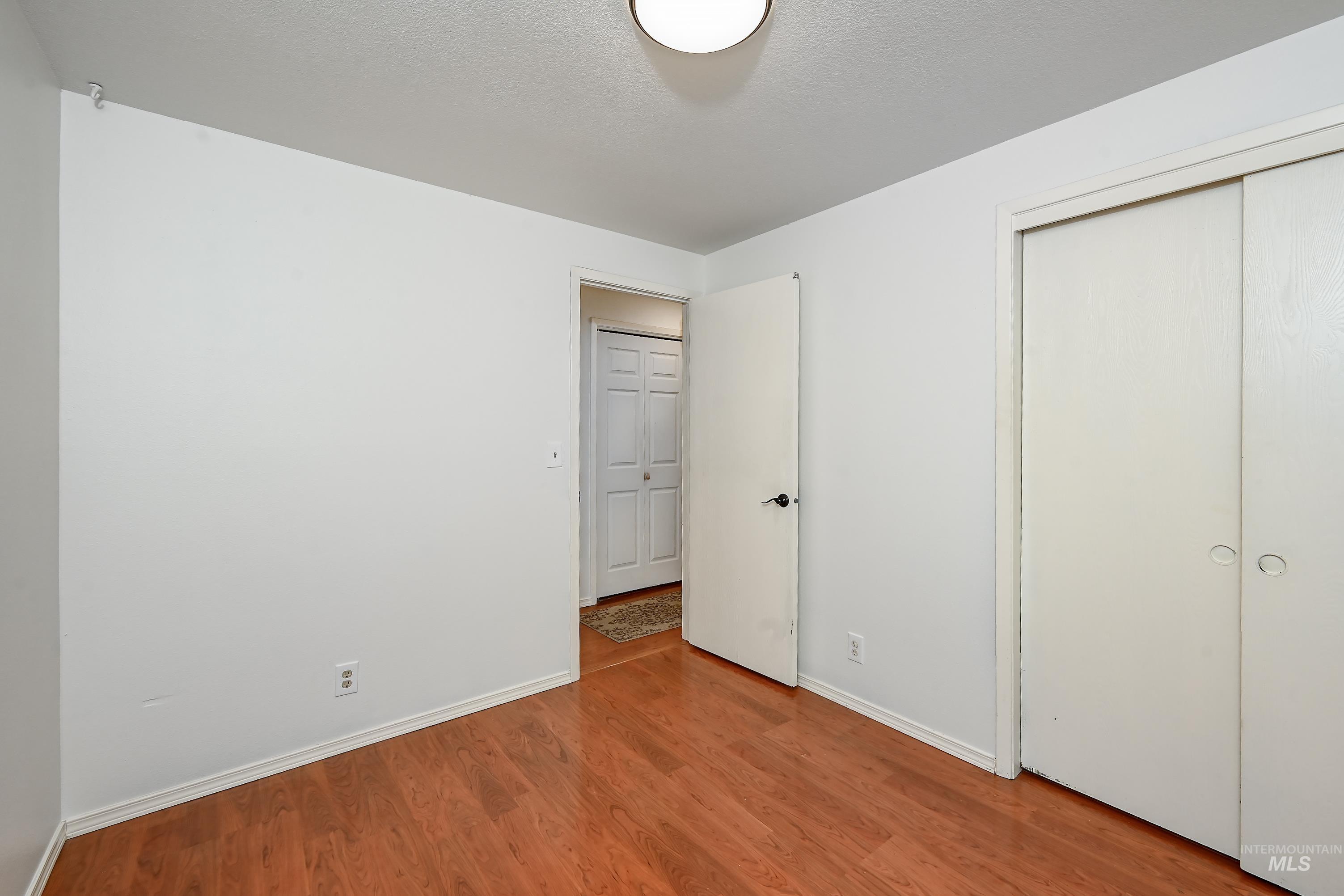 Unfurnished bedroom featuring wood finished floors, a closet, and a textured ceiling