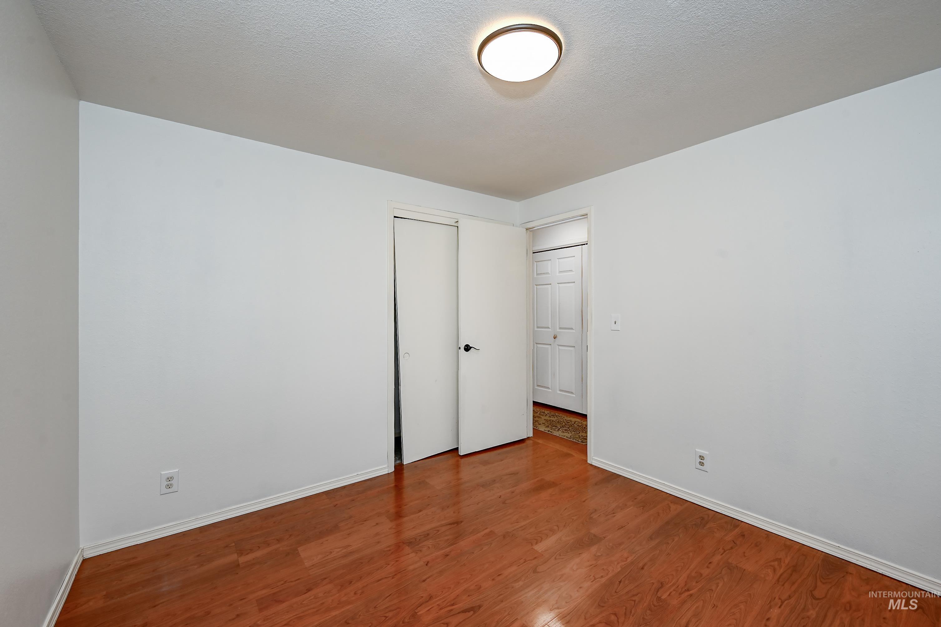 Unfurnished bedroom with wood finished floors, a textured ceiling, and a closet
