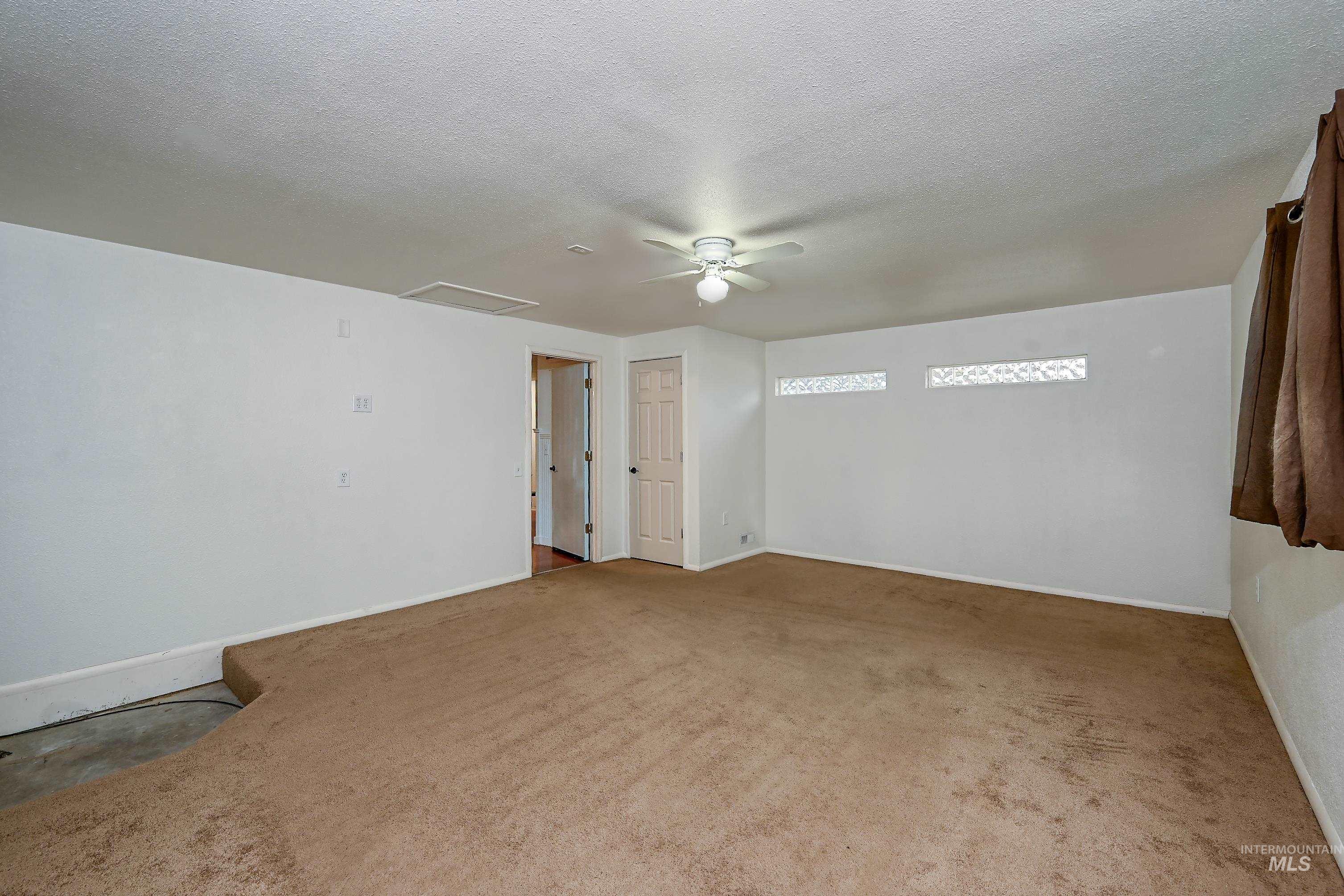 Spare room featuring a ceiling fan, a textured ceiling, and light carpet