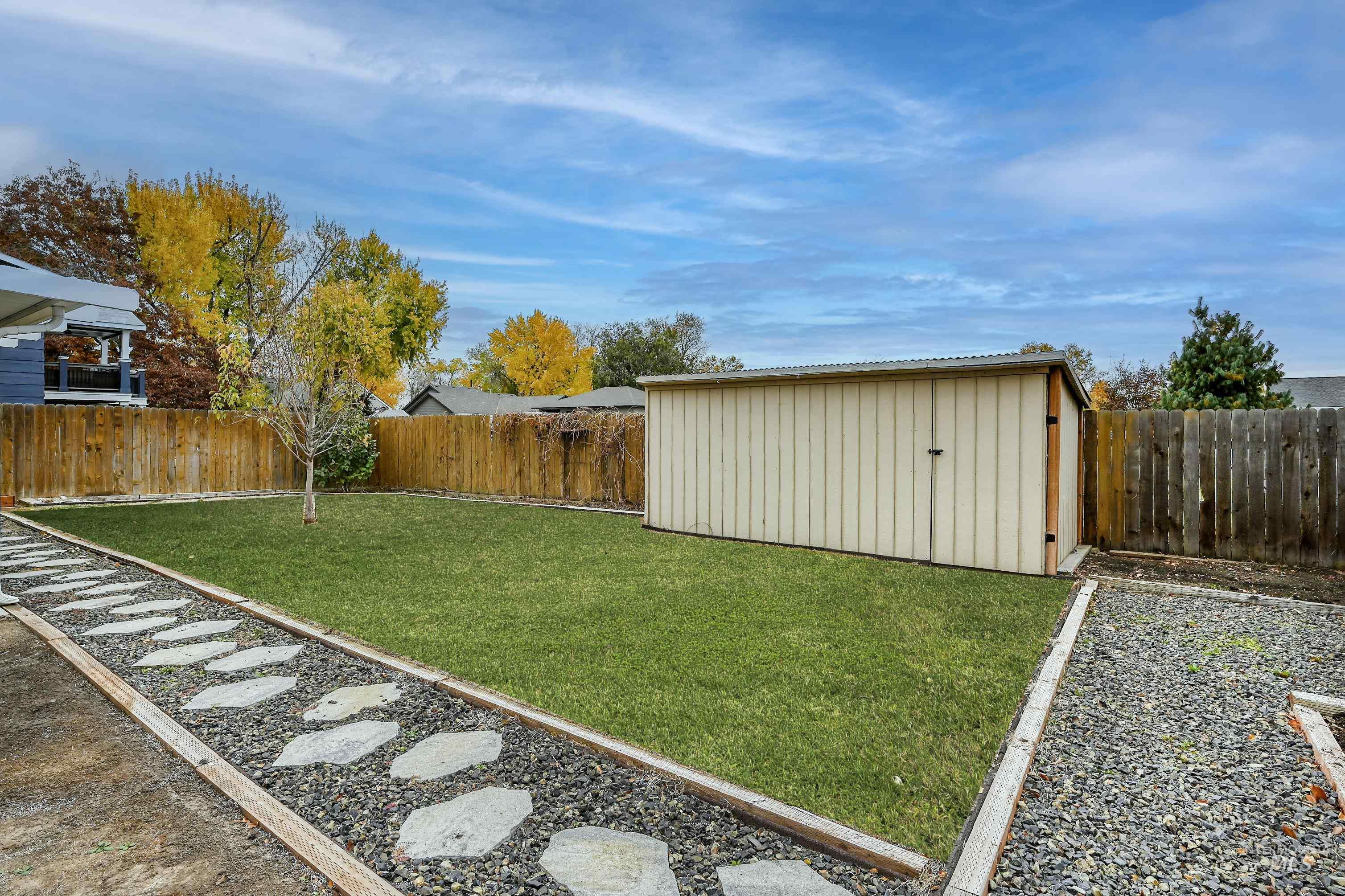 Fenced backyard featuring a storage unit