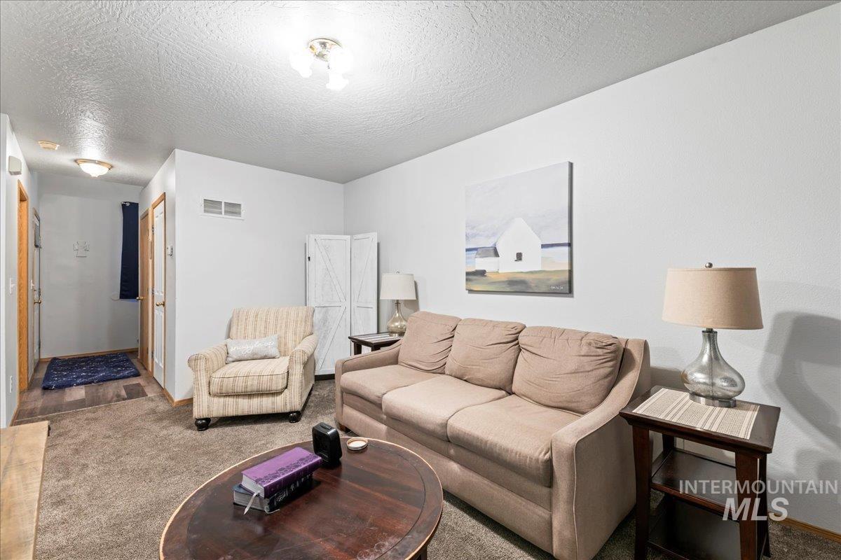 Carpeted living area featuring a textured ceiling and baseboards