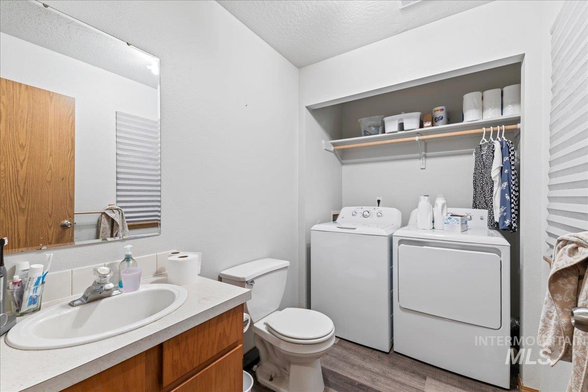Bathroom with a textured ceiling, washer and dryer, vanity, and wood finished floors