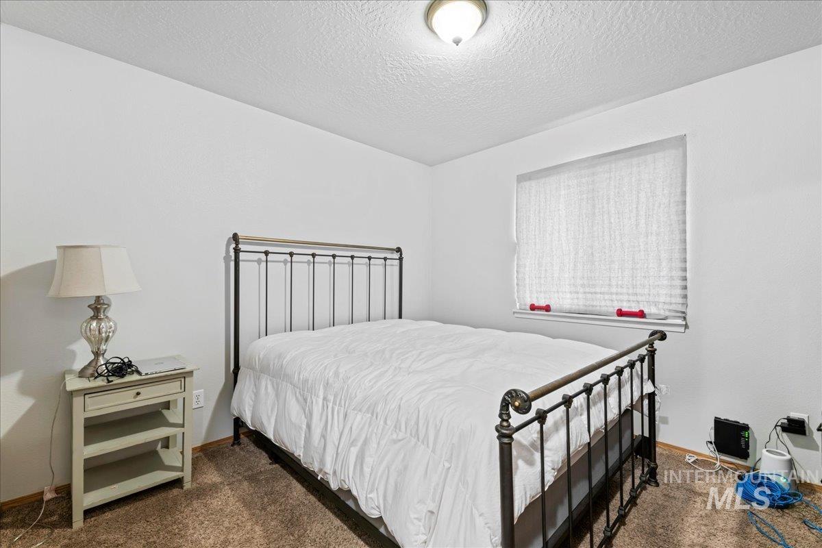Bedroom with dark colored carpet and a textured ceiling
