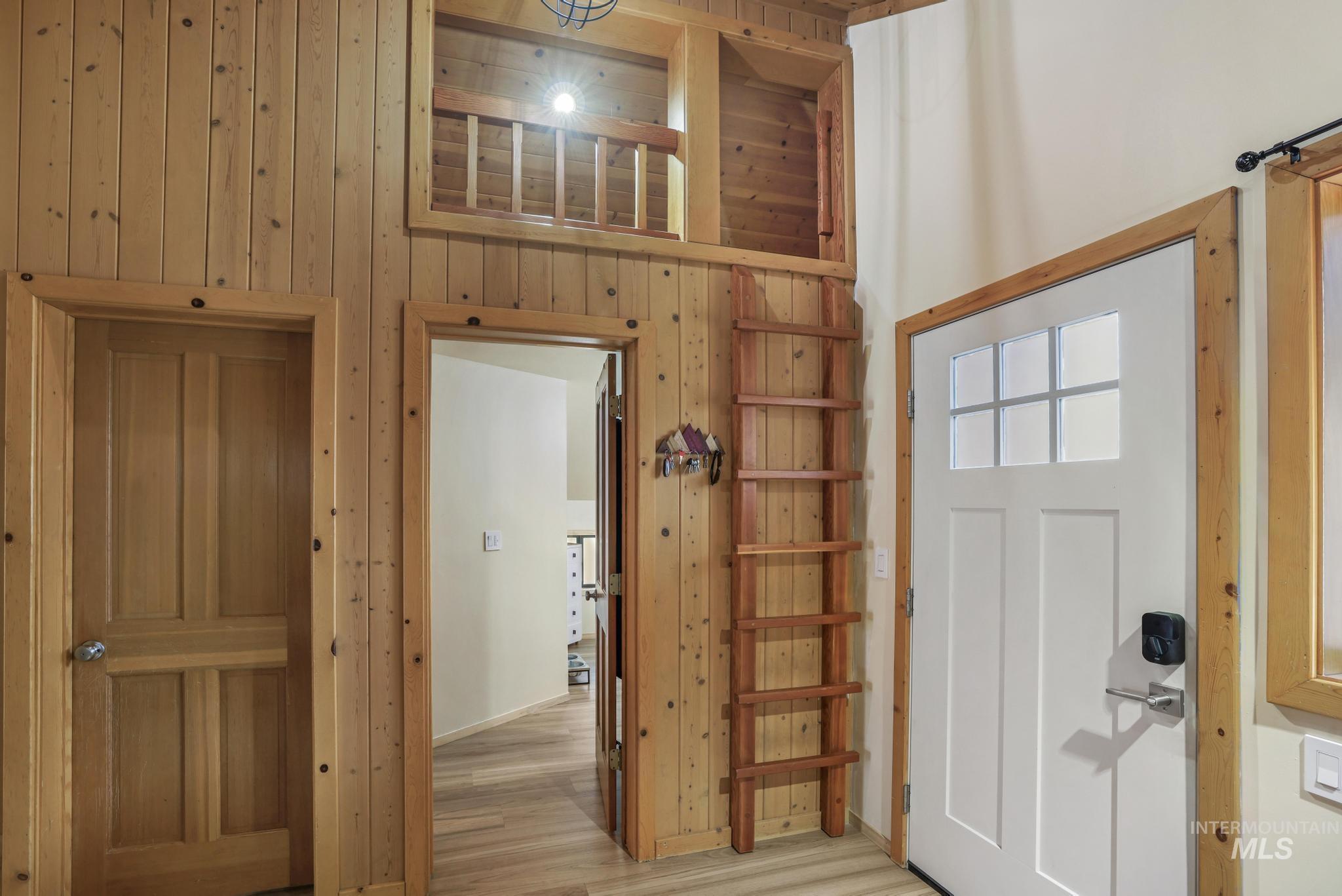 Entryway featuring wooden walls, a high ceiling, and wood finished floors