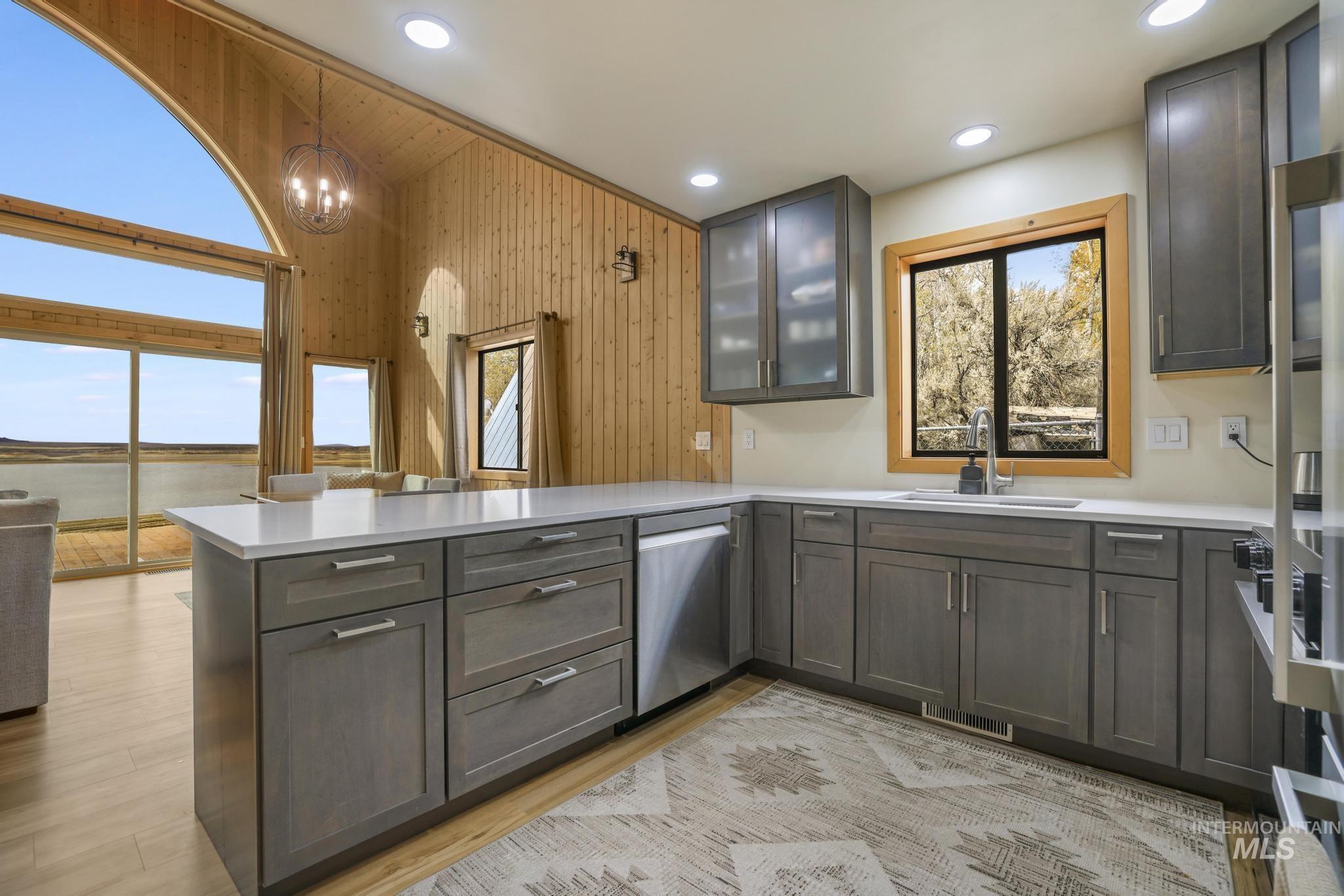 Kitchen featuring glass insert cabinets, pendant lighting, a peninsula, dishwasher, and recessed lighting