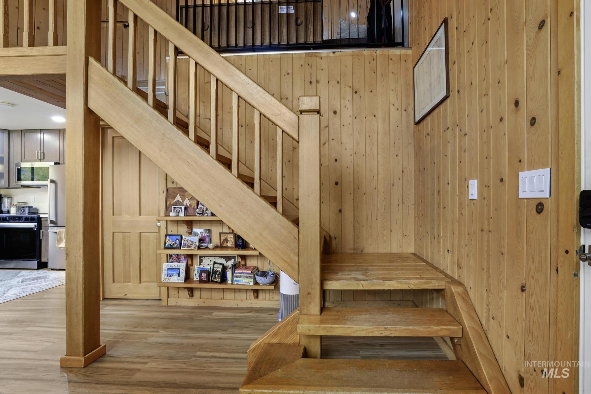 Stairway featuring wood finished floors and wood walls