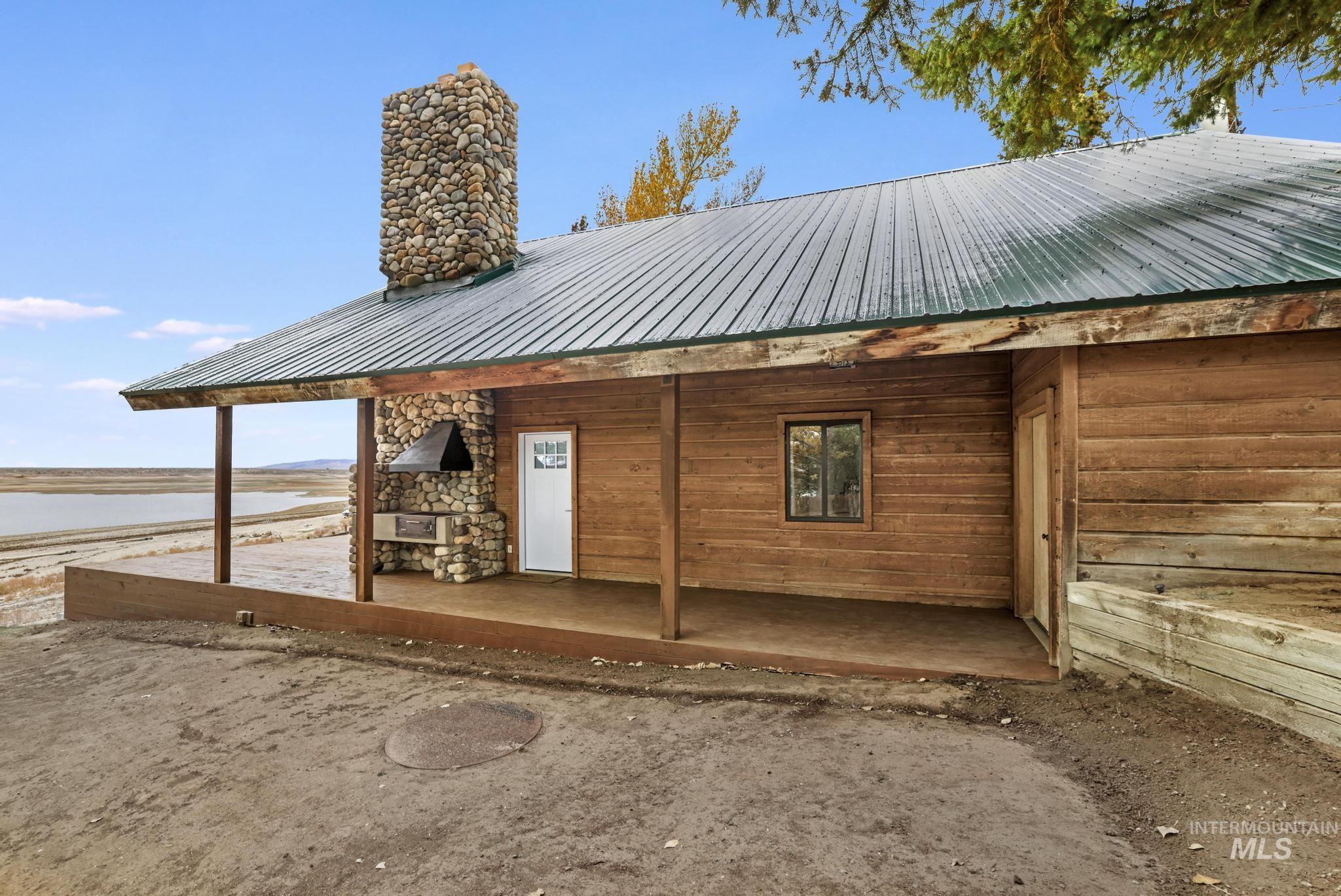 Back of property featuring a metal roof, a water view, and a chimney