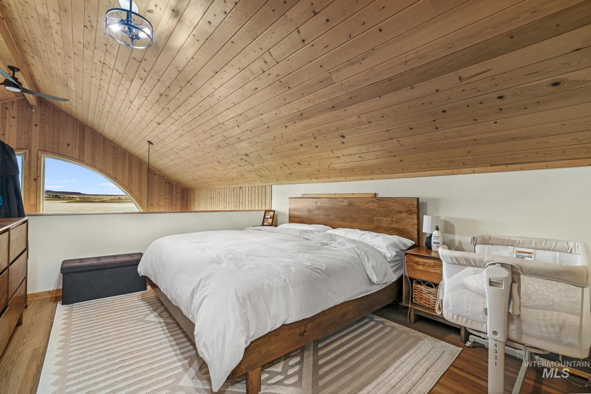 Bedroom with vaulted ceiling, light wood finished floors, and wooden ceiling