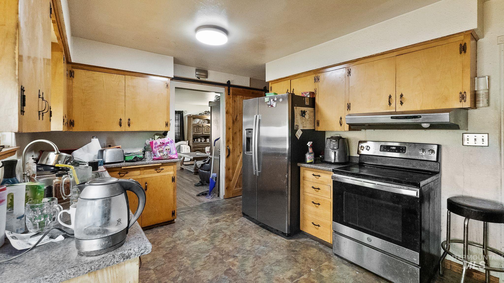 Kitchen with appliances with stainless steel finishes, a barn door, and under cabinet range hood