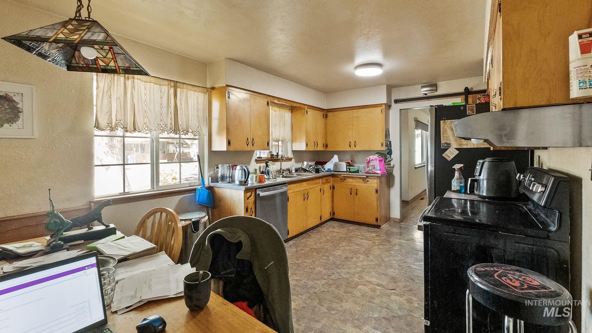 Kitchen featuring black electric range, a barn door, plenty of natural light, stainless steel dishwasher, and a textured wall