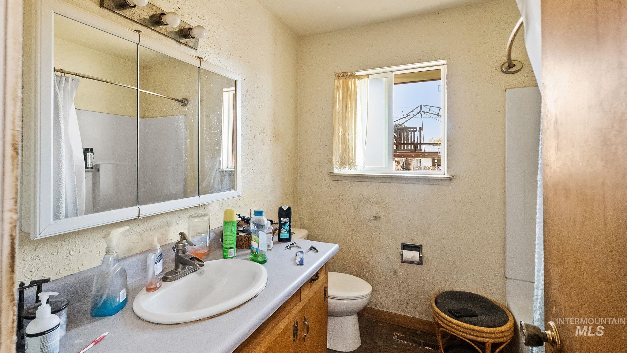 Bathroom with a shower with shower curtain, a textured wall, and vanity