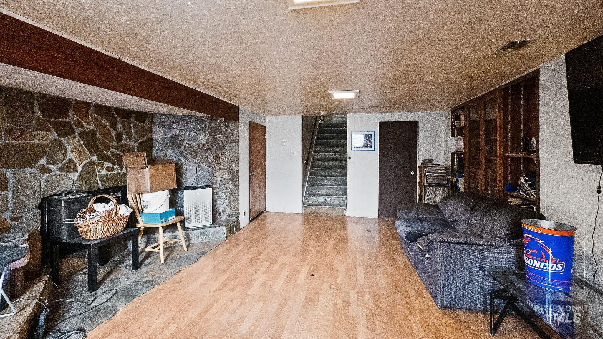 Living room with a textured ceiling, wood finished floors, stairs, and a wood stove