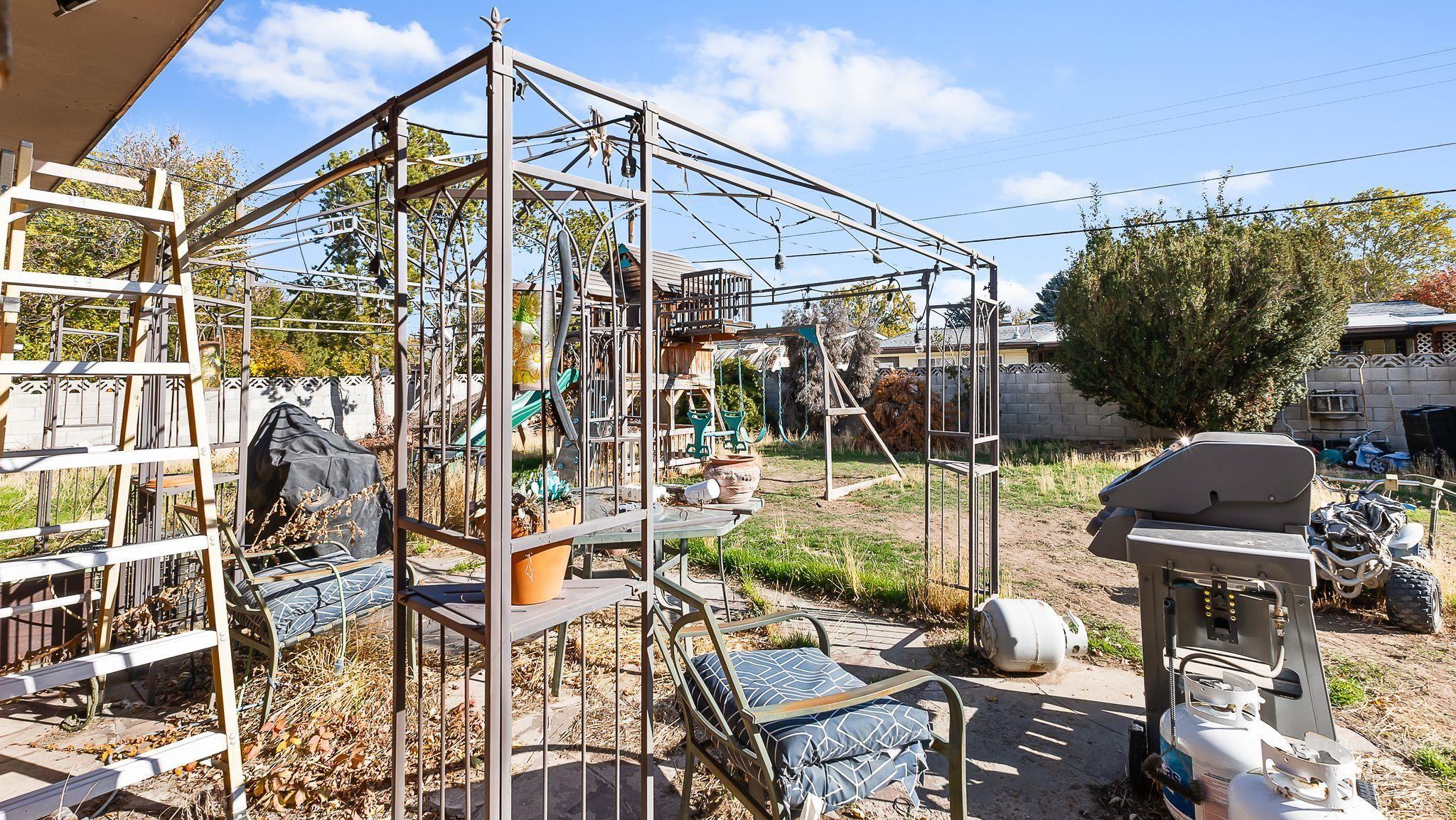 Fenced backyard with a grill and a playground
