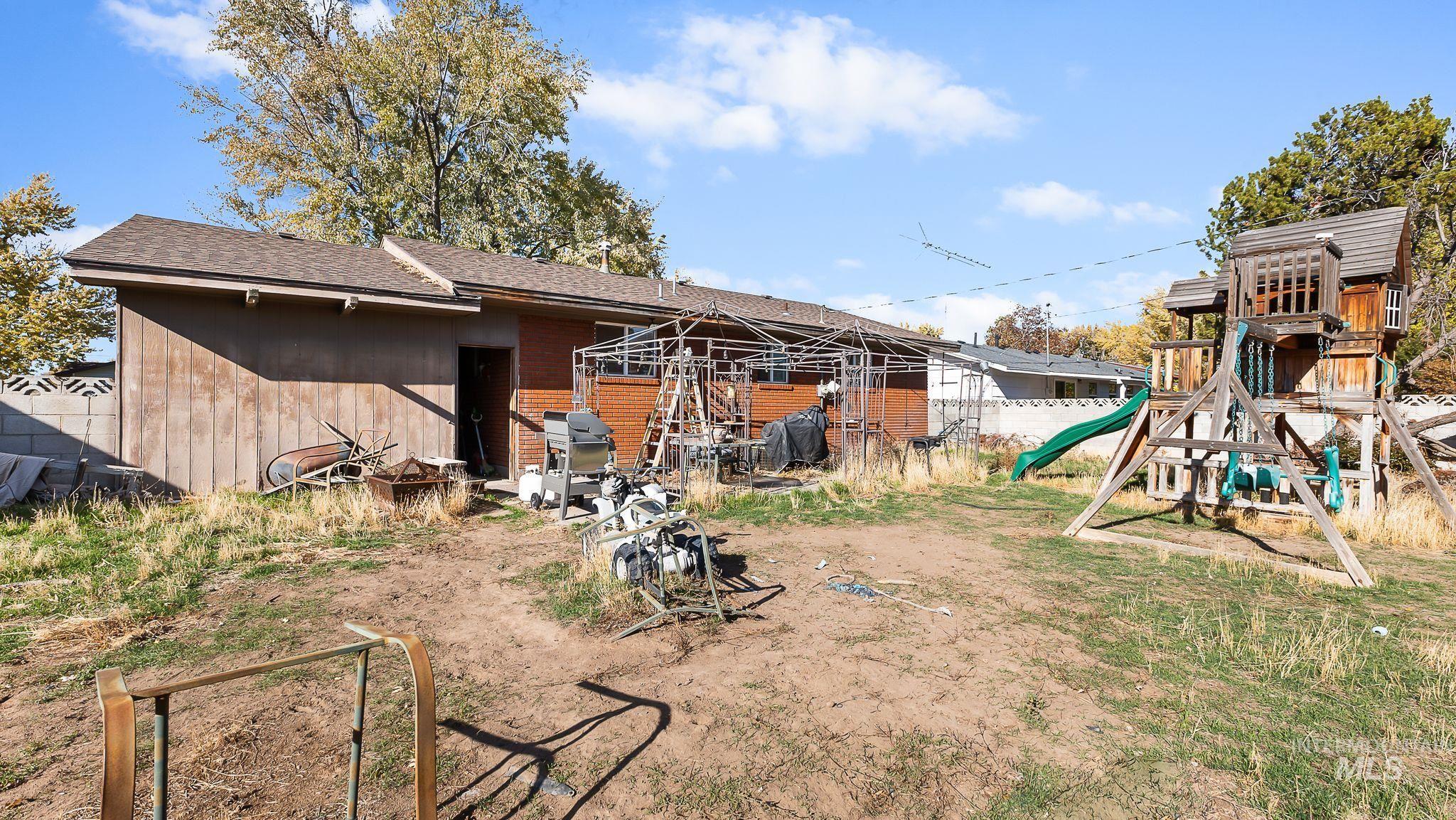 Rear view of property with a playground, roof with shingles, a patio, and brick siding
