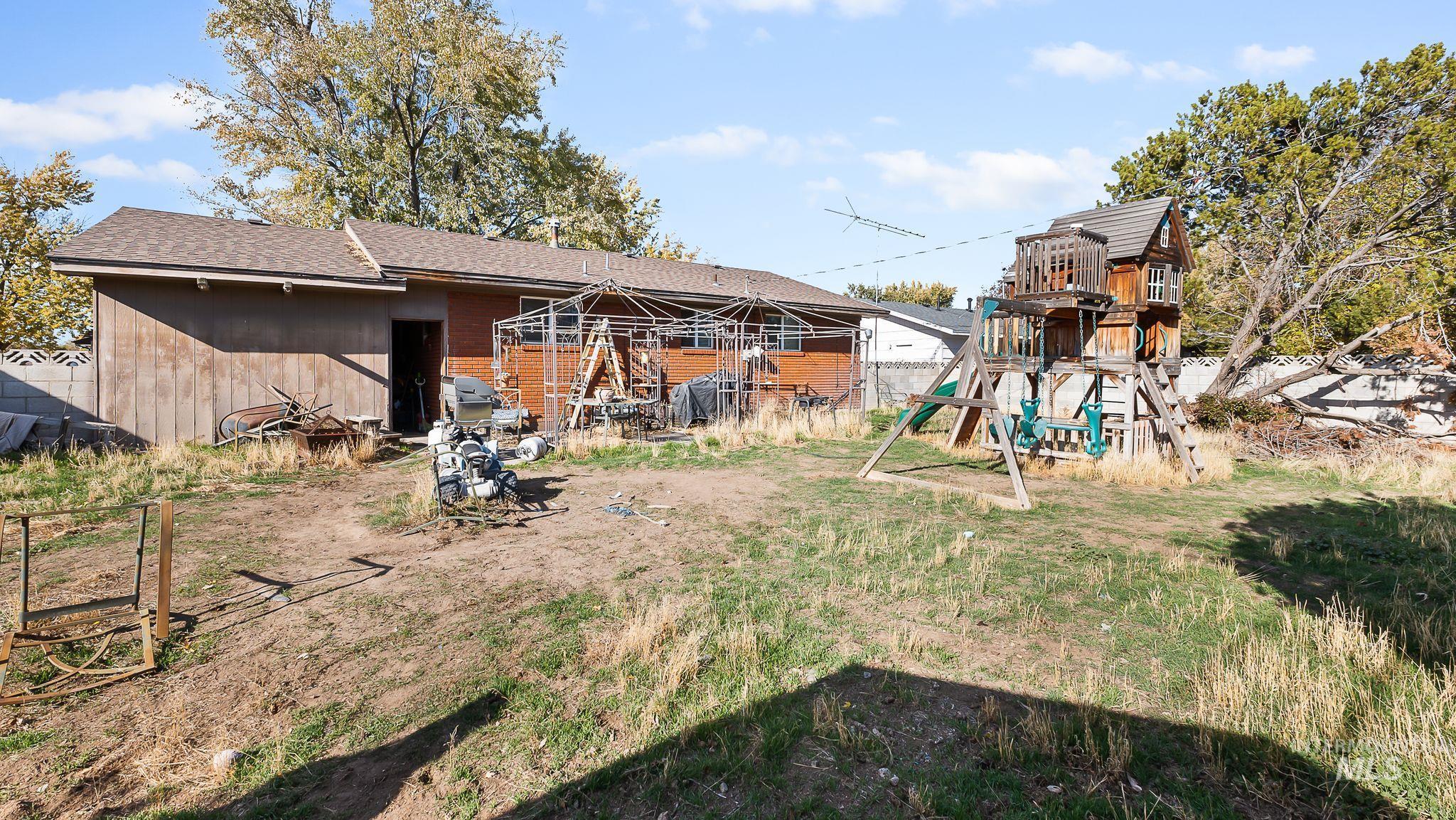 Back of property with roof with shingles and a playground
