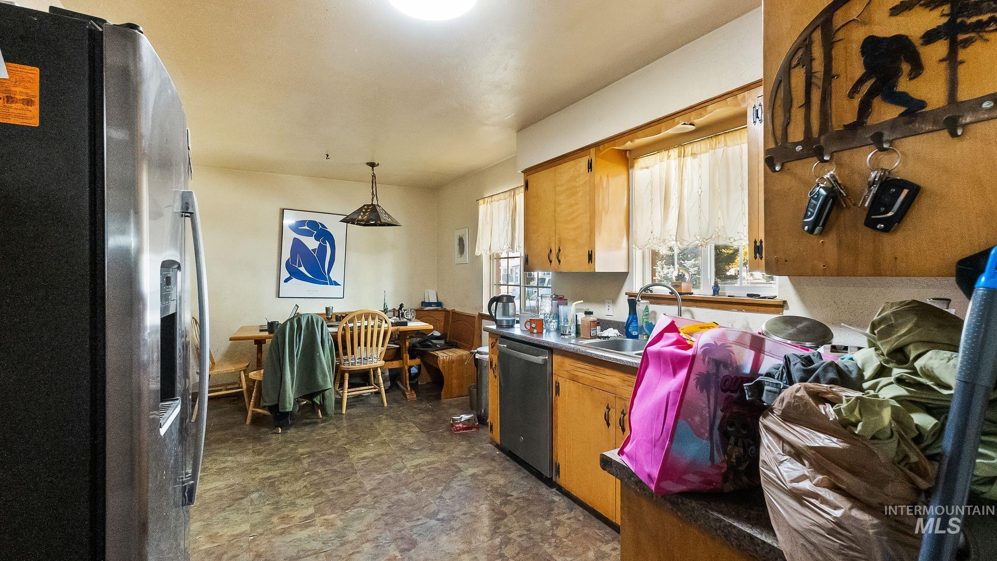Kitchen featuring stainless steel appliances, decorative light fixtures, and brown cabinets