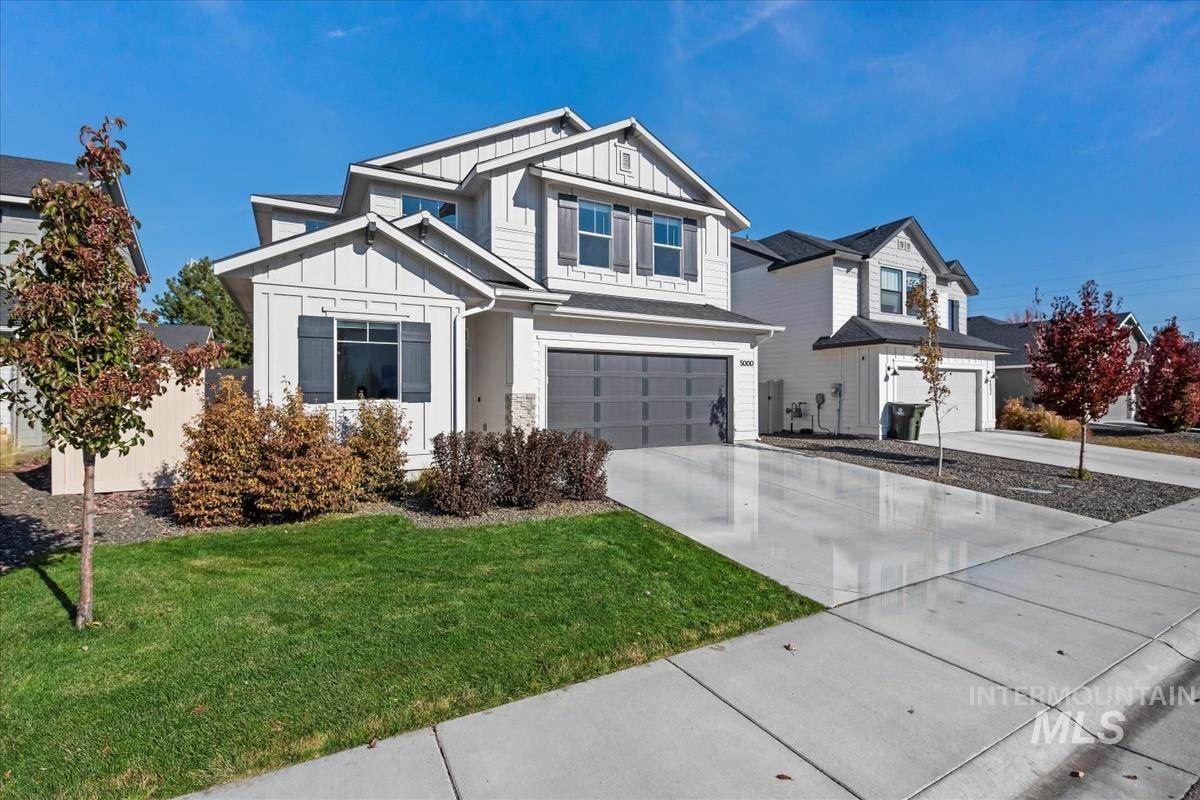 View of front of home with board and batten siding, driveway, a garage, and a front lawn