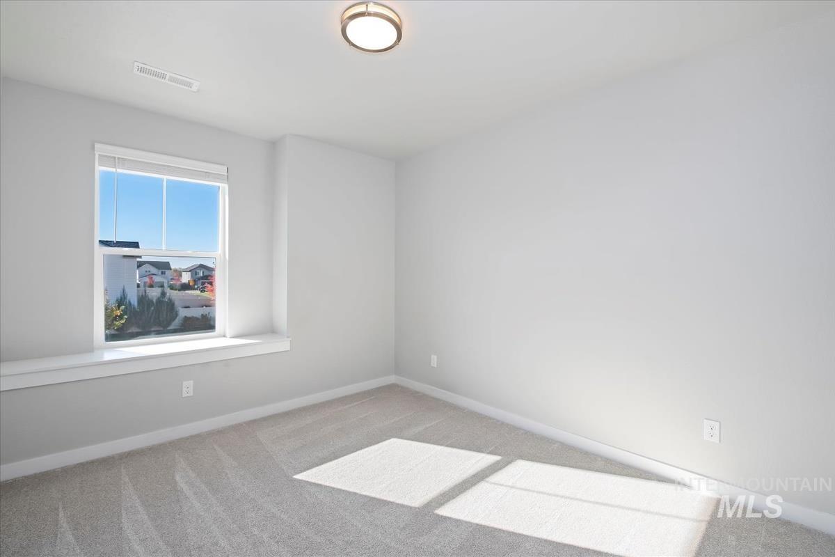 Carpeted spare room featuring baseboards