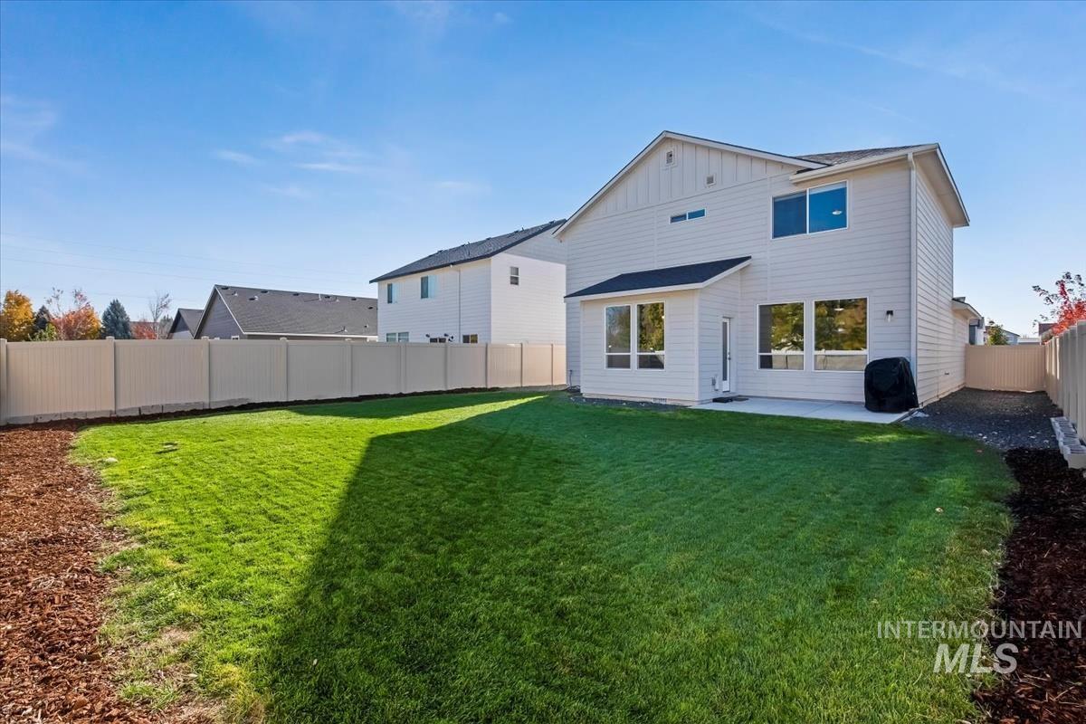 Rear view of house with a fenced backyard, a patio, and board and batten siding