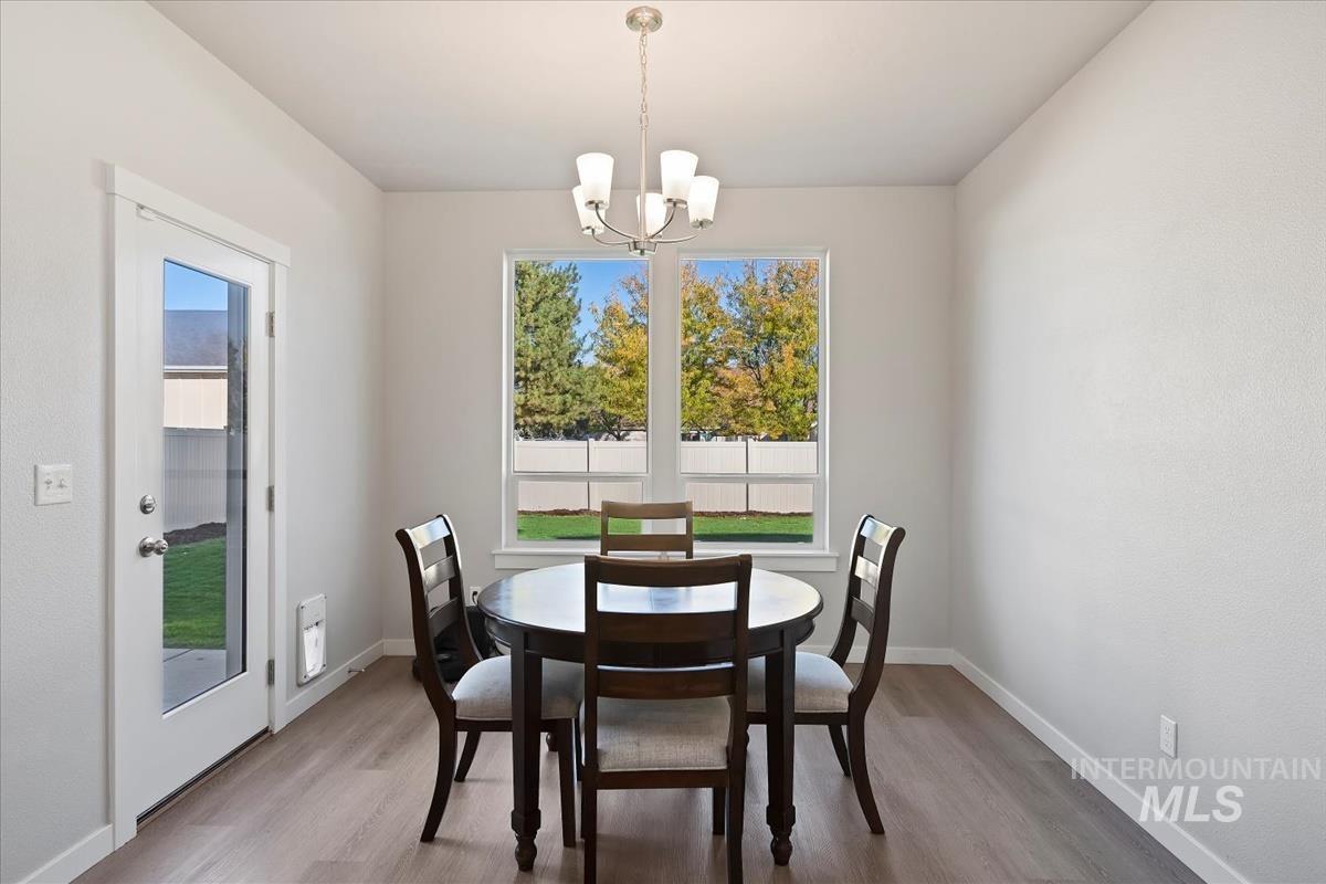 Dining space featuring wood finished floors, healthy amount of natural light, and a chandelier