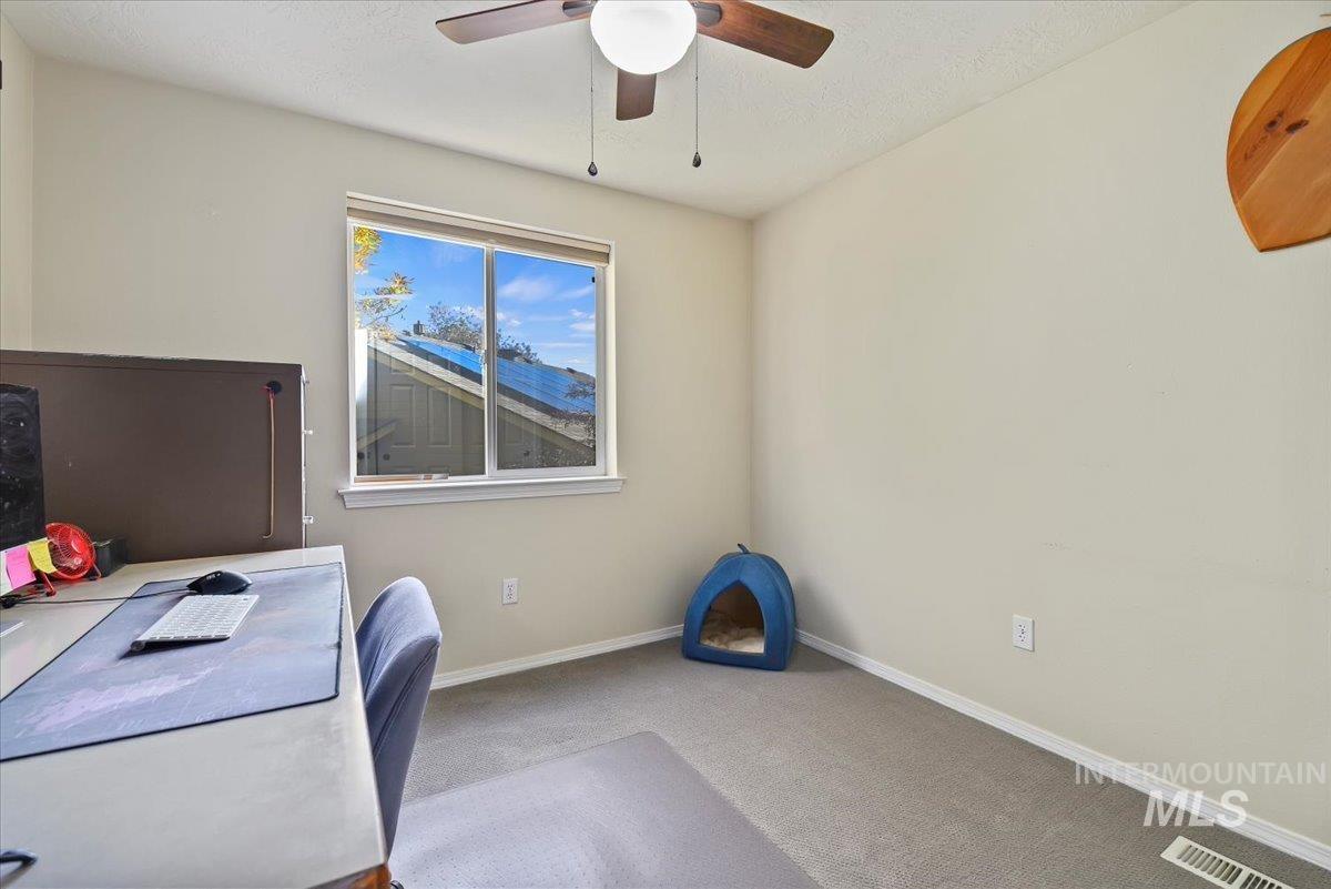 Carpeted office featuring ceiling fan and a textured ceiling