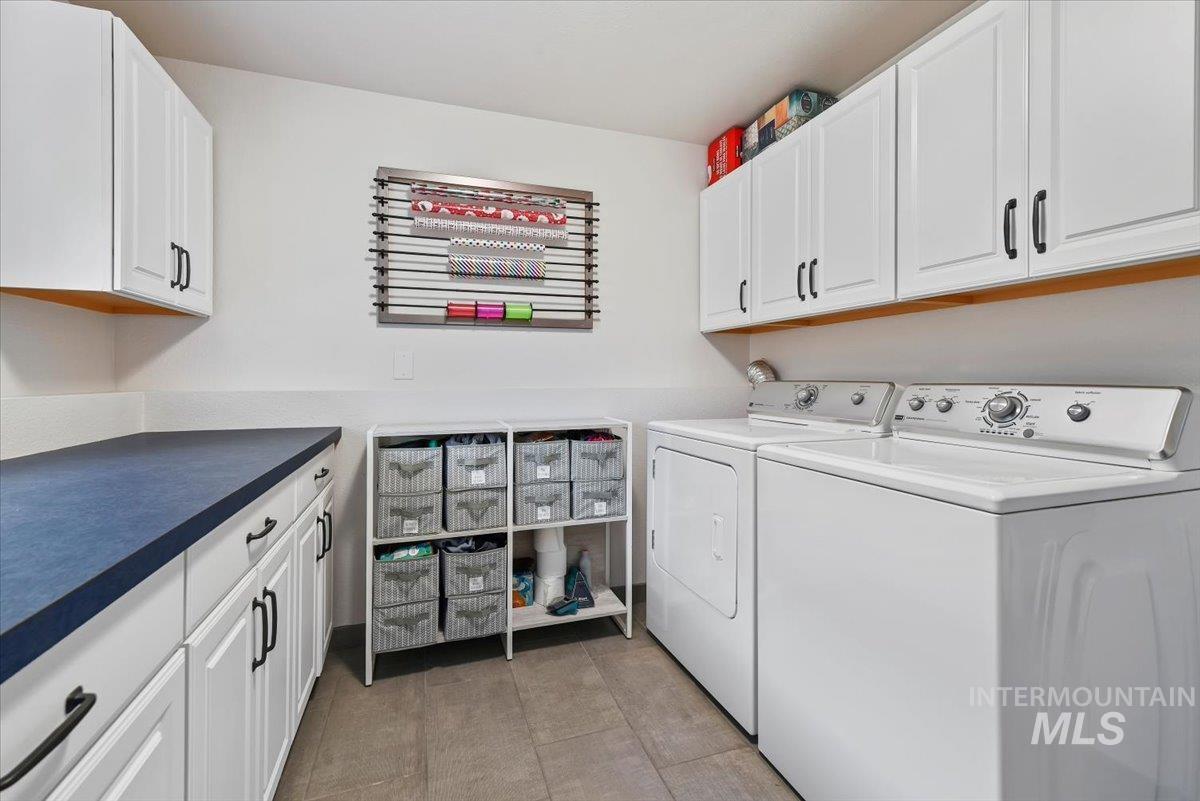 Laundry room with cabinet space, independent washer and dryer, and light tile patterned floors