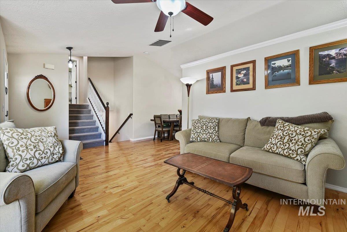 Living room with stairs, light wood-style floors, and ceiling fan