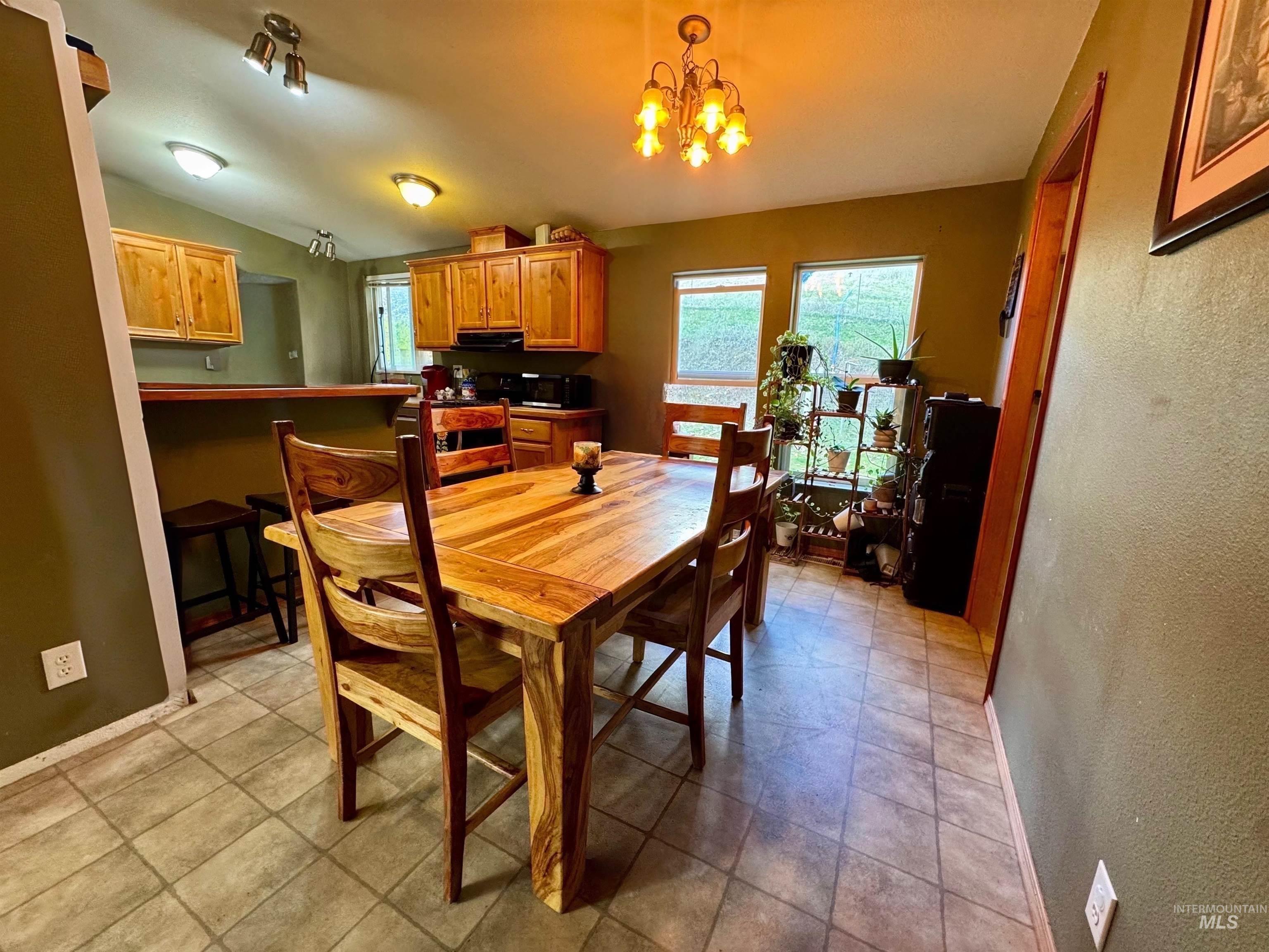 Dining room featuring a textured wall, a chandelier, and lofted ceiling