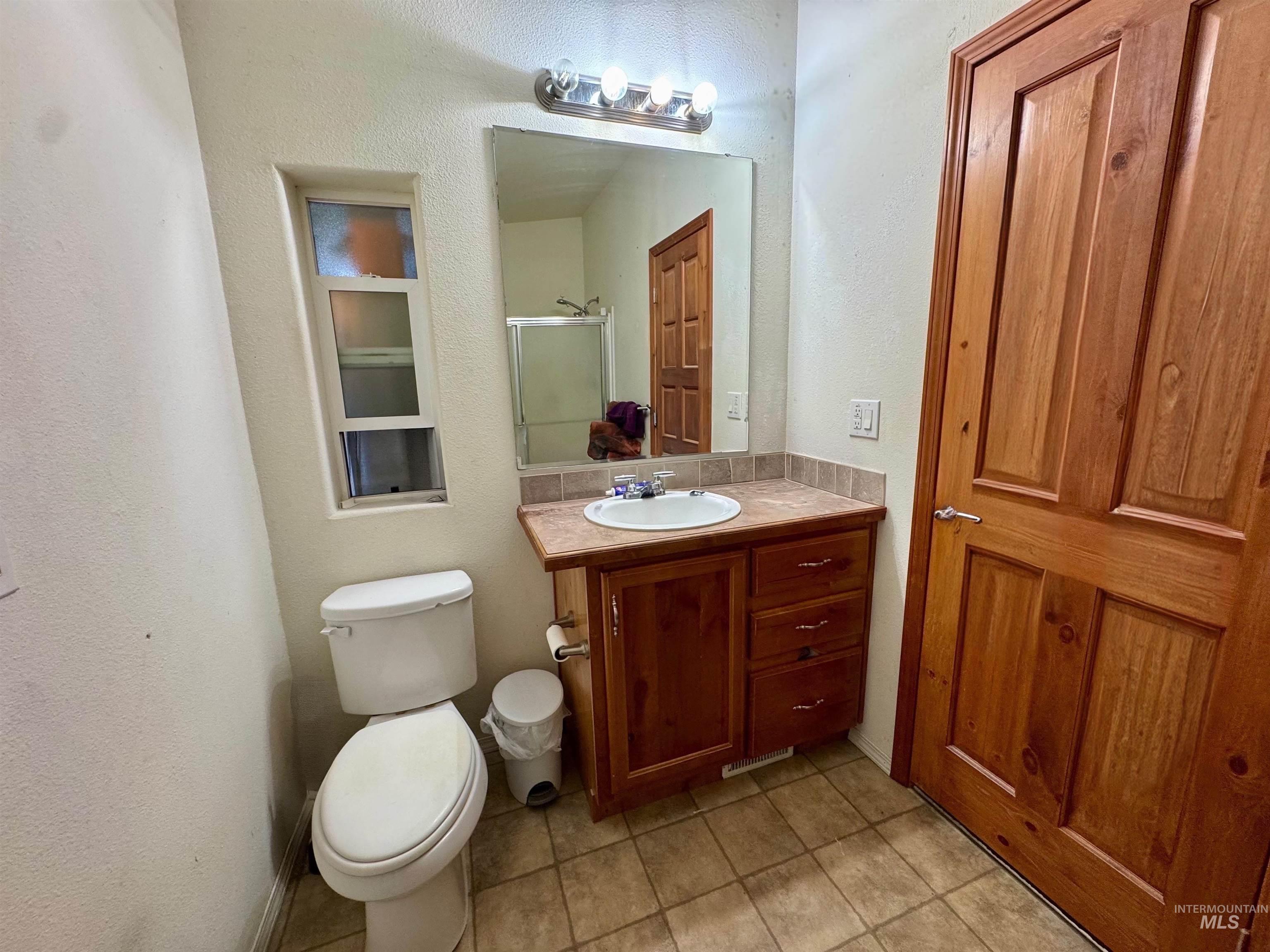 Bathroom with vanity, light tile patterned flooring, a stall shower, and a textured wall