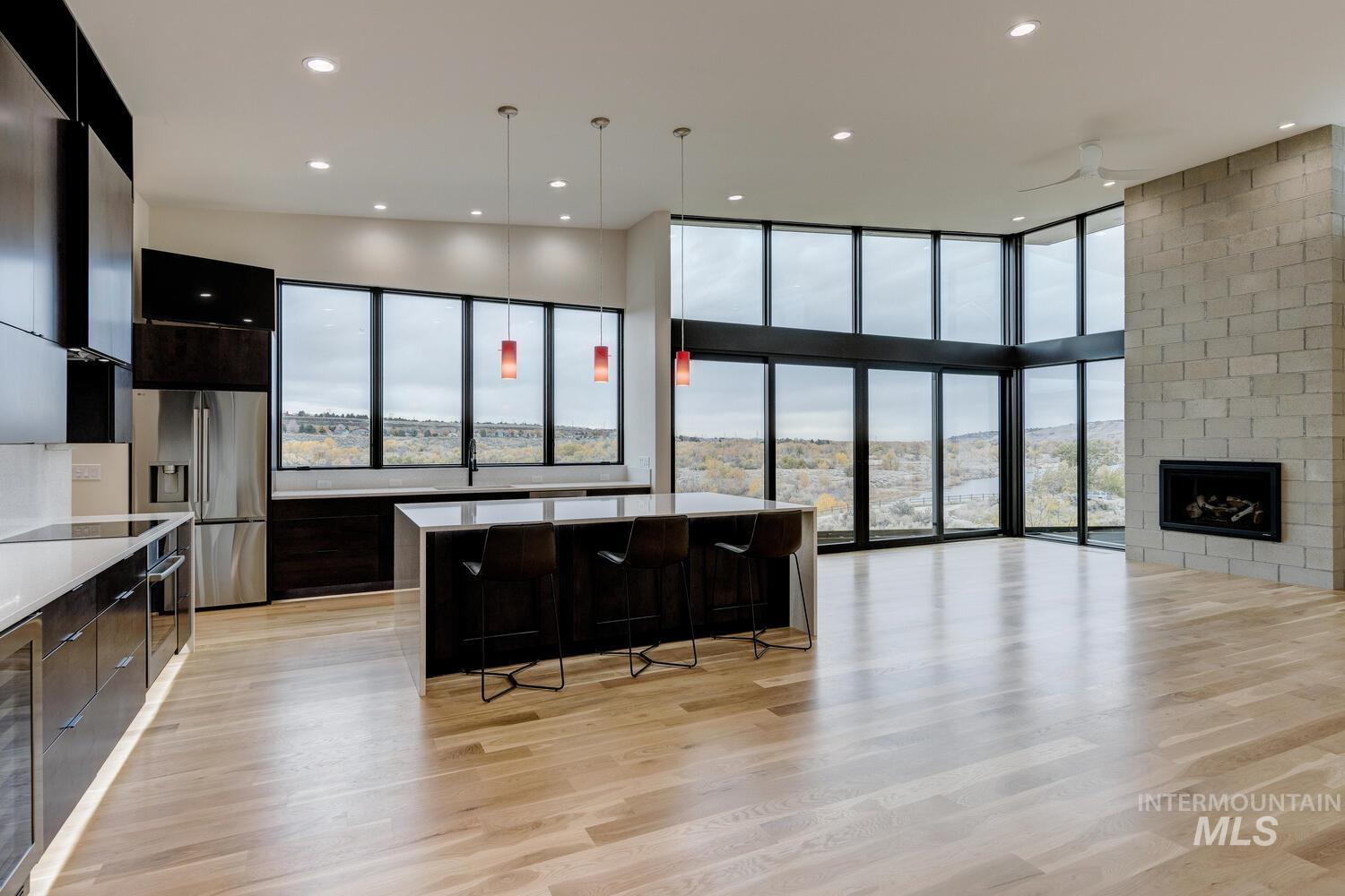 Kitchen with a kitchen breakfast bar, open floor plan, appliances with stainless steel finishes, dark cabinets, and floor to ceiling windows