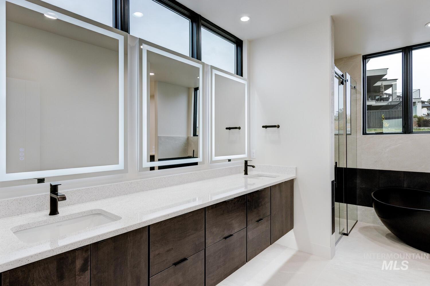 Full bathroom with double vanity, a shower stall, a soaking tub, light tile patterned floors, and recessed lighting