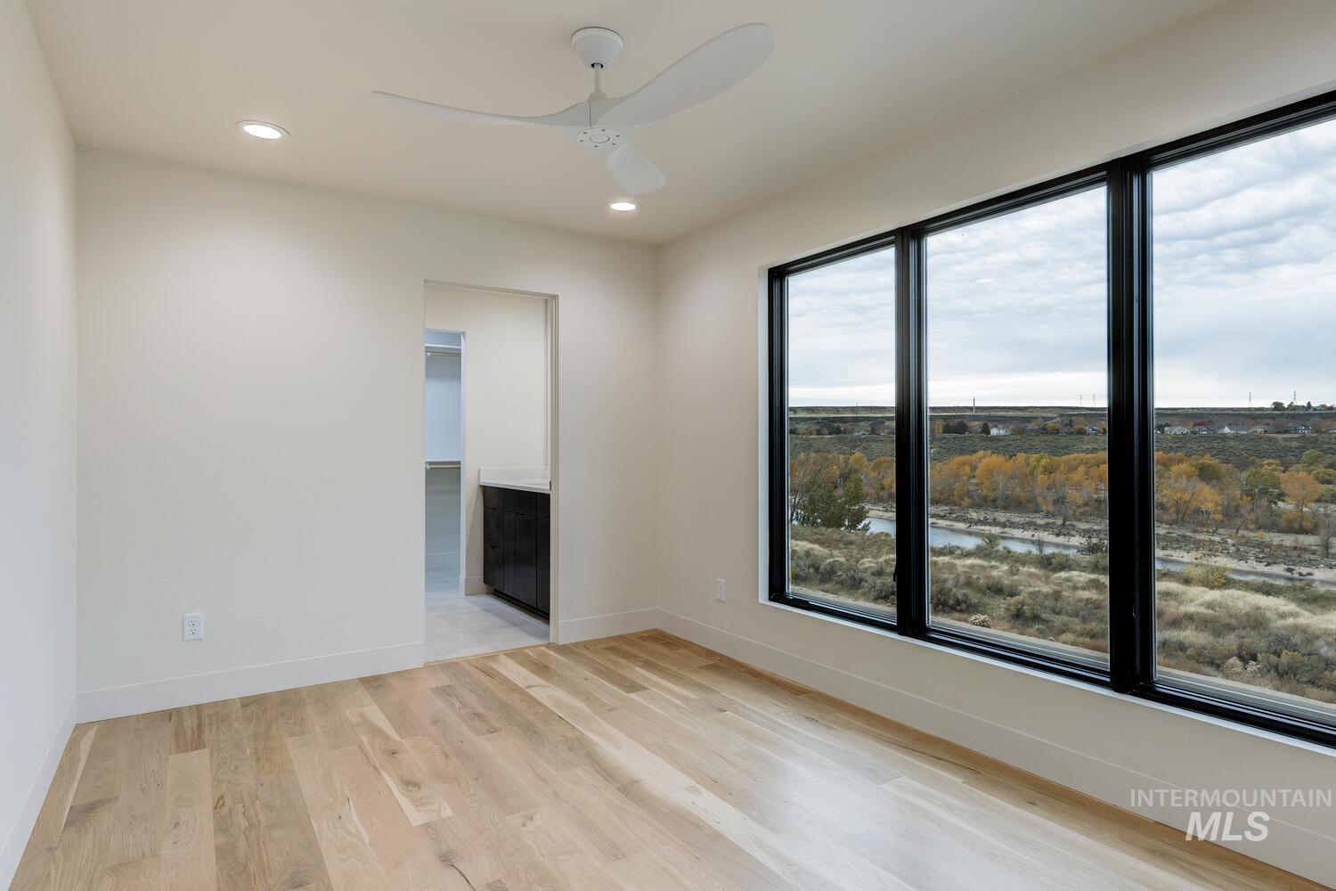 Unfurnished room featuring recessed lighting, light wood-type flooring, ceiling fan, and a water view