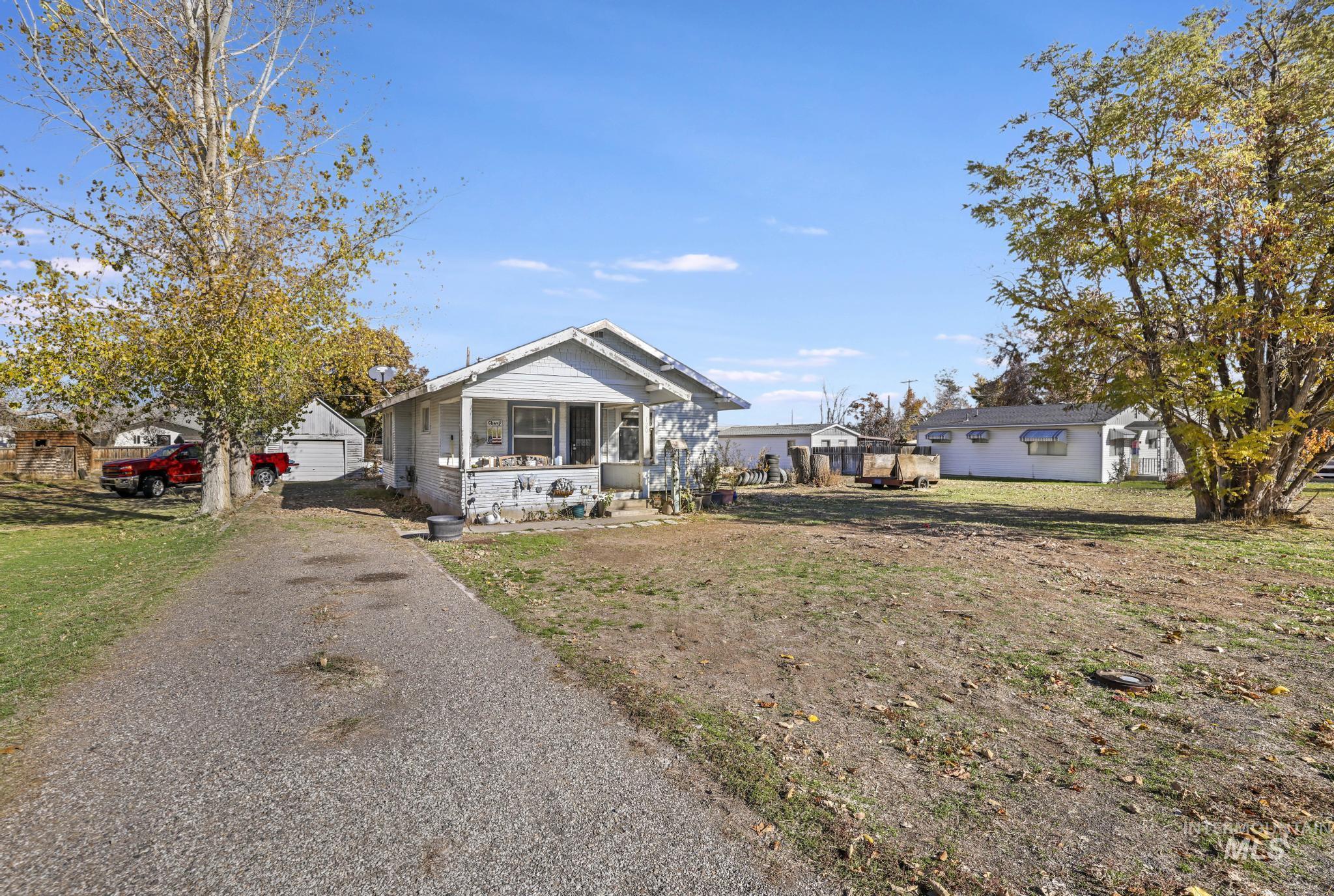 View of front of property featuring a sunroom, a front lawn, and a detached garage