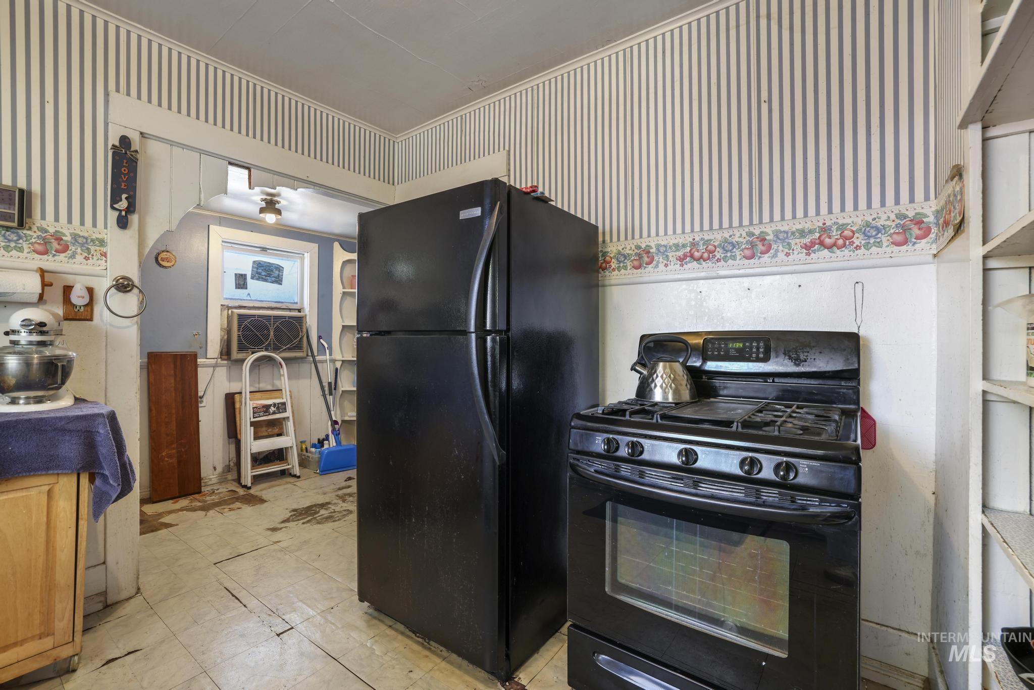 Kitchen with black appliances and wallpapered walls