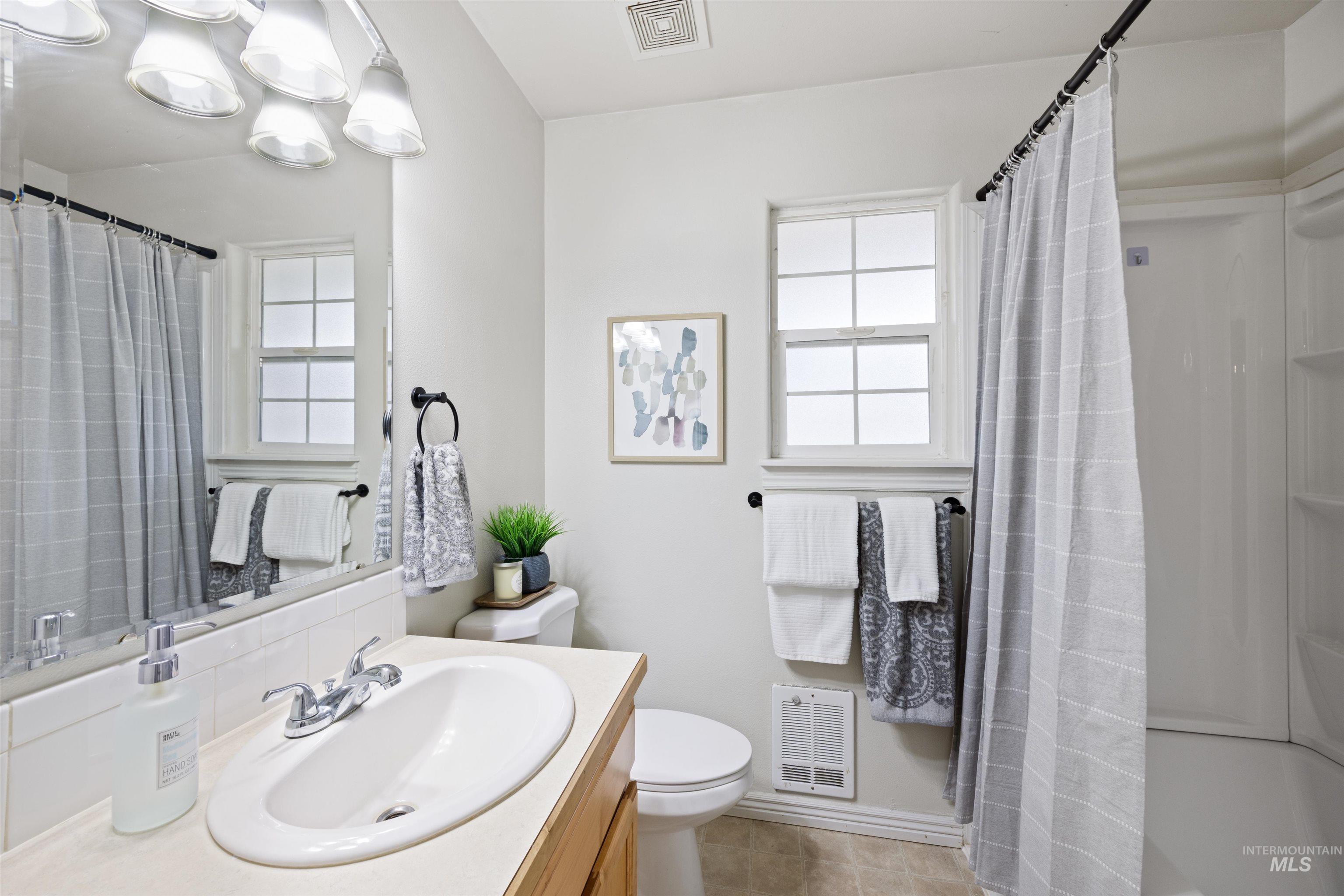 Full bathroom with vanity, heating unit, curtained shower, and light tile patterned flooring