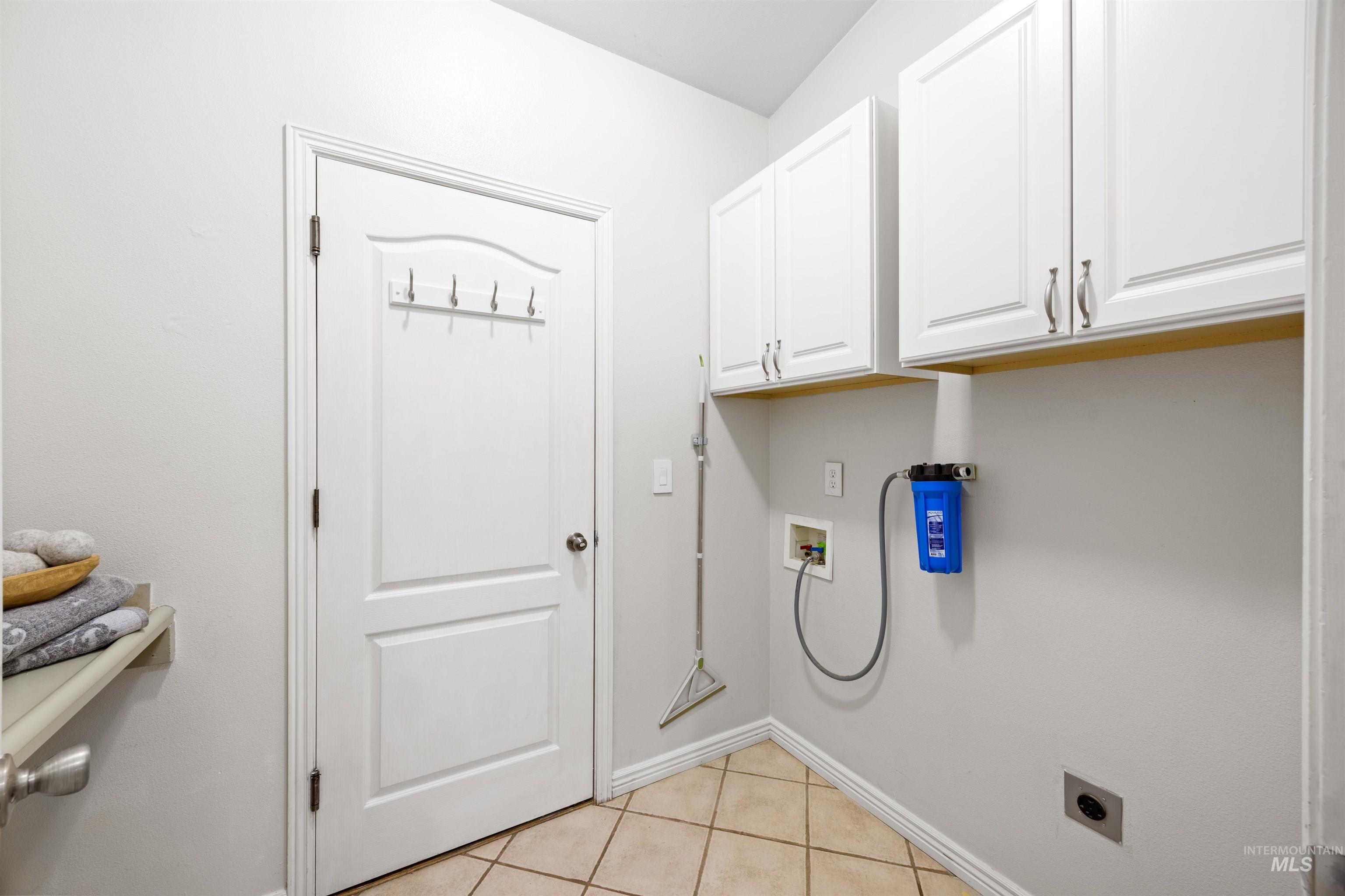 Laundry room with light tile patterned floors, cabinet space, hookup for a washing machine, and hookup for an electric dryer