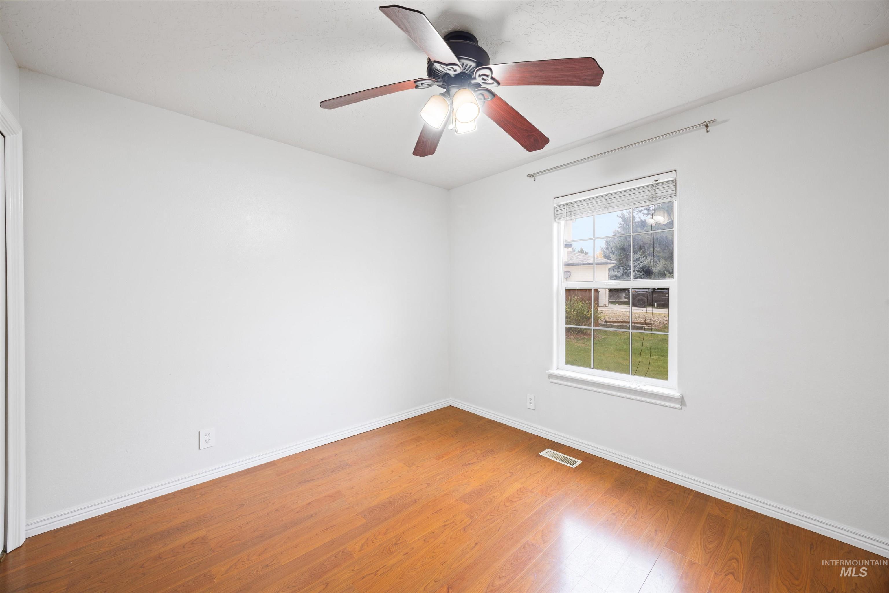 Empty room featuring light wood-style flooring and a ceiling fan