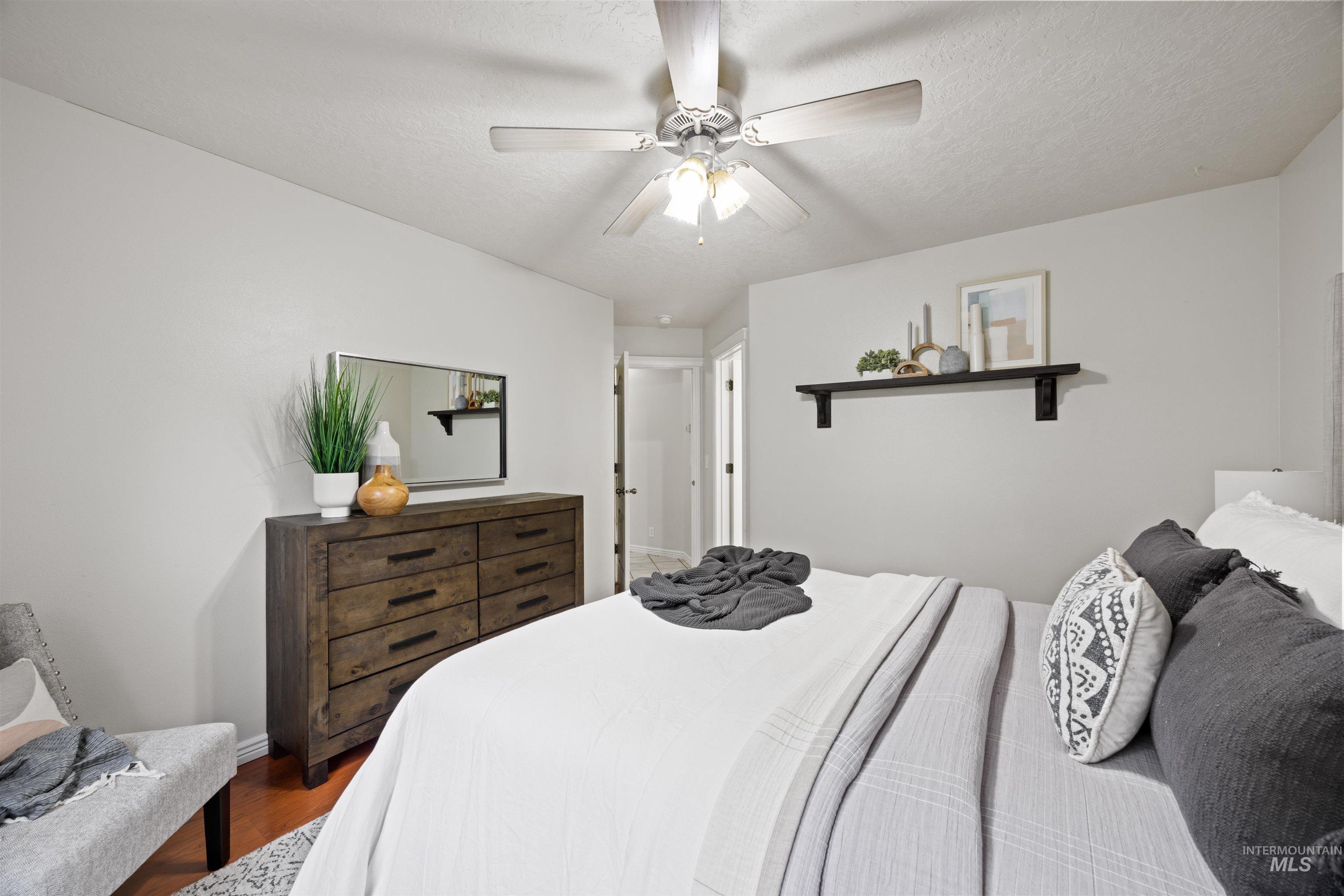 Bedroom with wood finished floors, a ceiling fan, and a textured ceiling