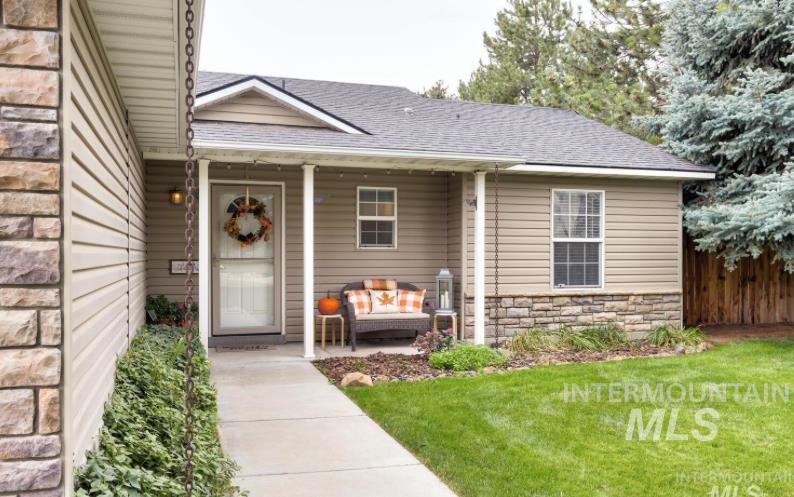 Entrance to property with stone siding, a porch, and a shingled roof