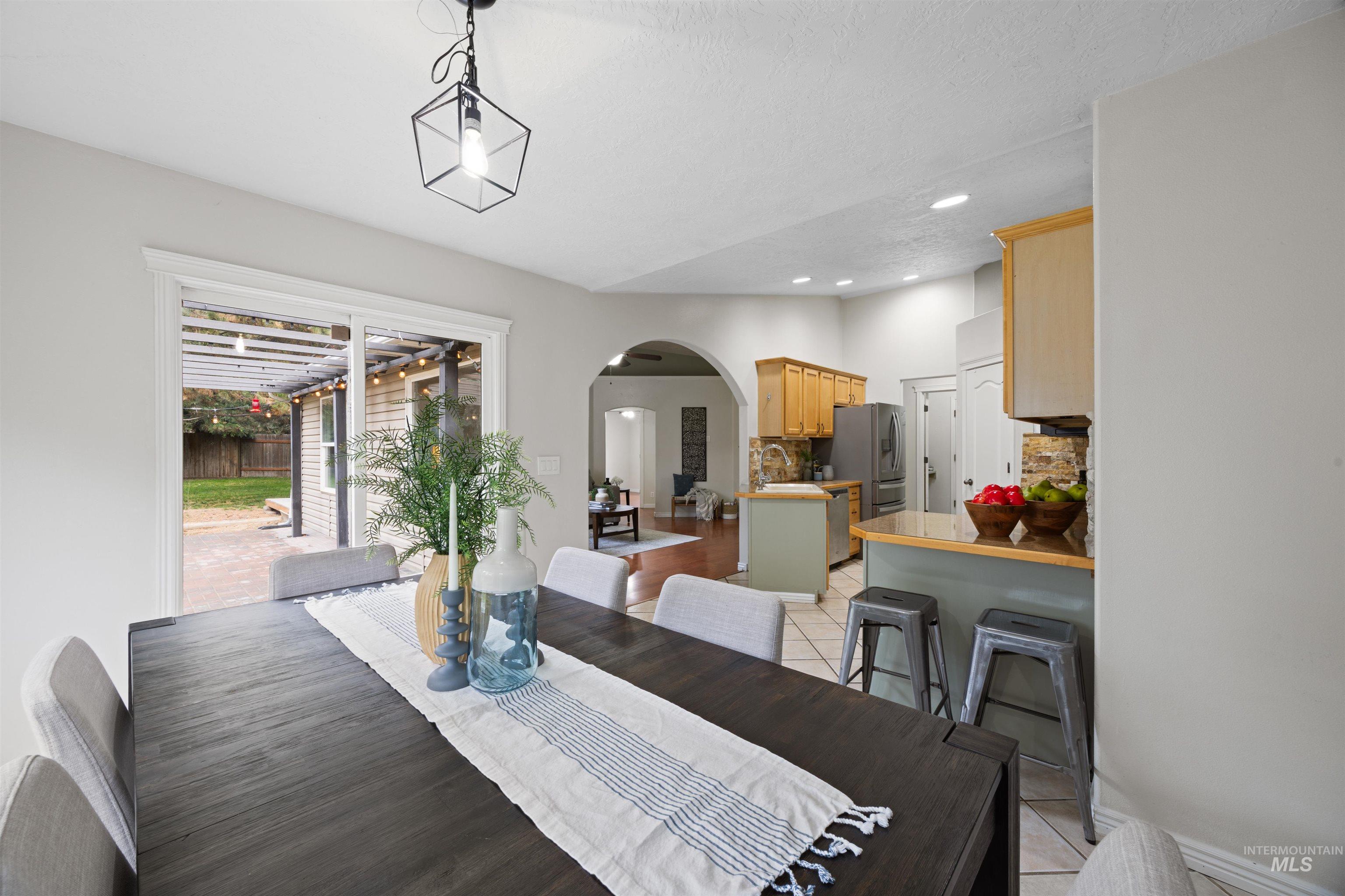 Dining space featuring arched walkways, light tile patterned floors, and recessed lighting