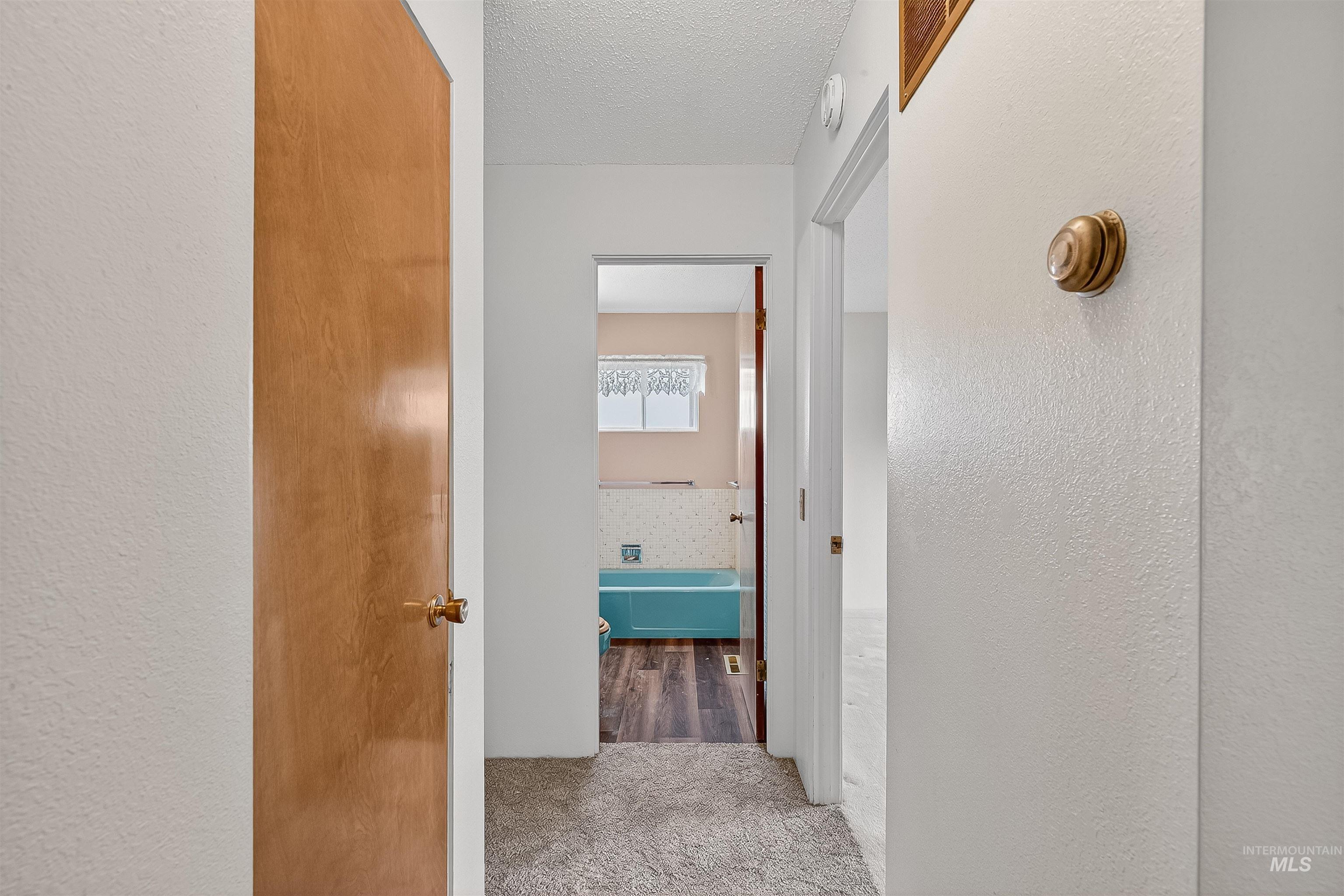 Hall with carpet, a textured ceiling, and a textured wall