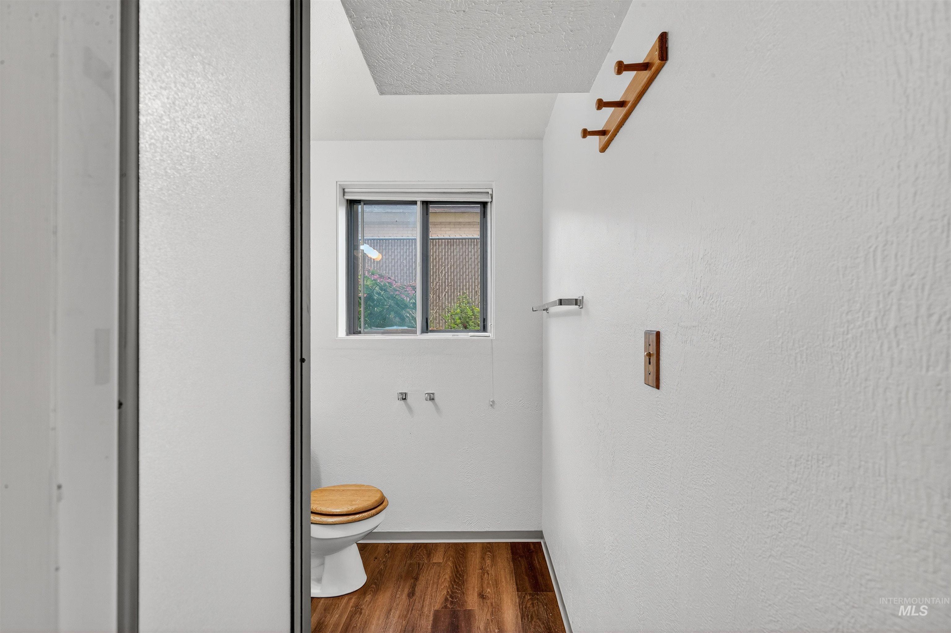 Half bath featuring dark wood-type flooring, a textured wall, and a textured ceiling