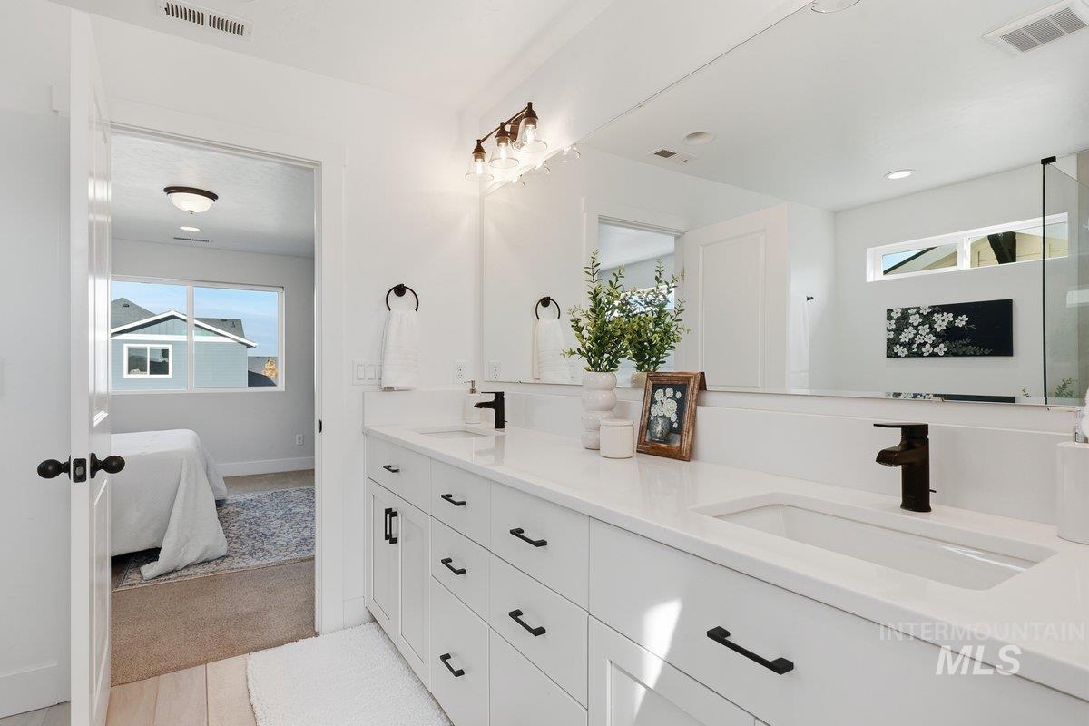 Bathroom with double vanity, ensuite bathroom, and light carpet