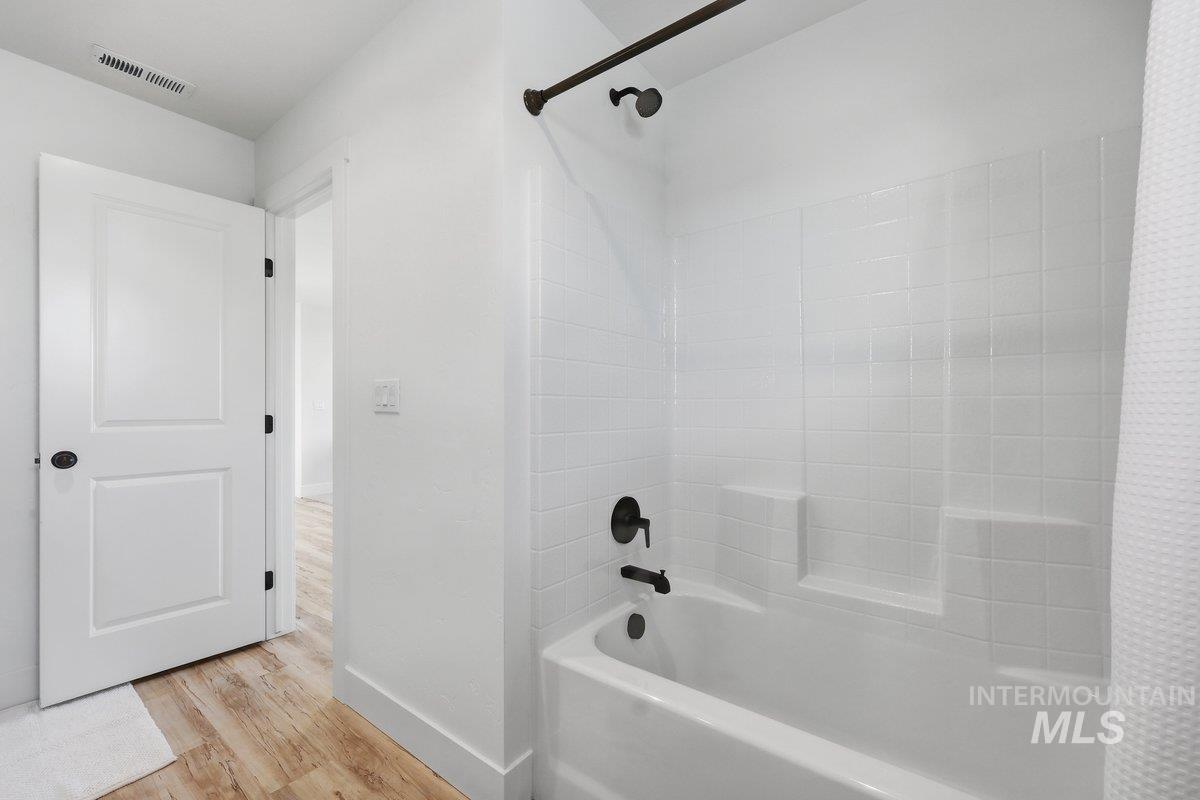 Bathroom with shower / bath combo with shower curtain and light wood-style flooring